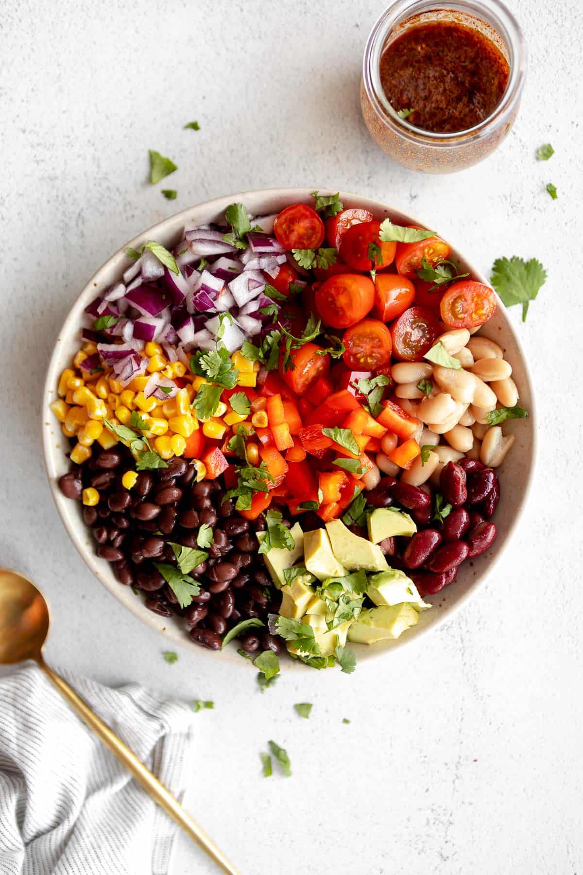 mexican bean salad with tomatoes, beans and dressing on the side