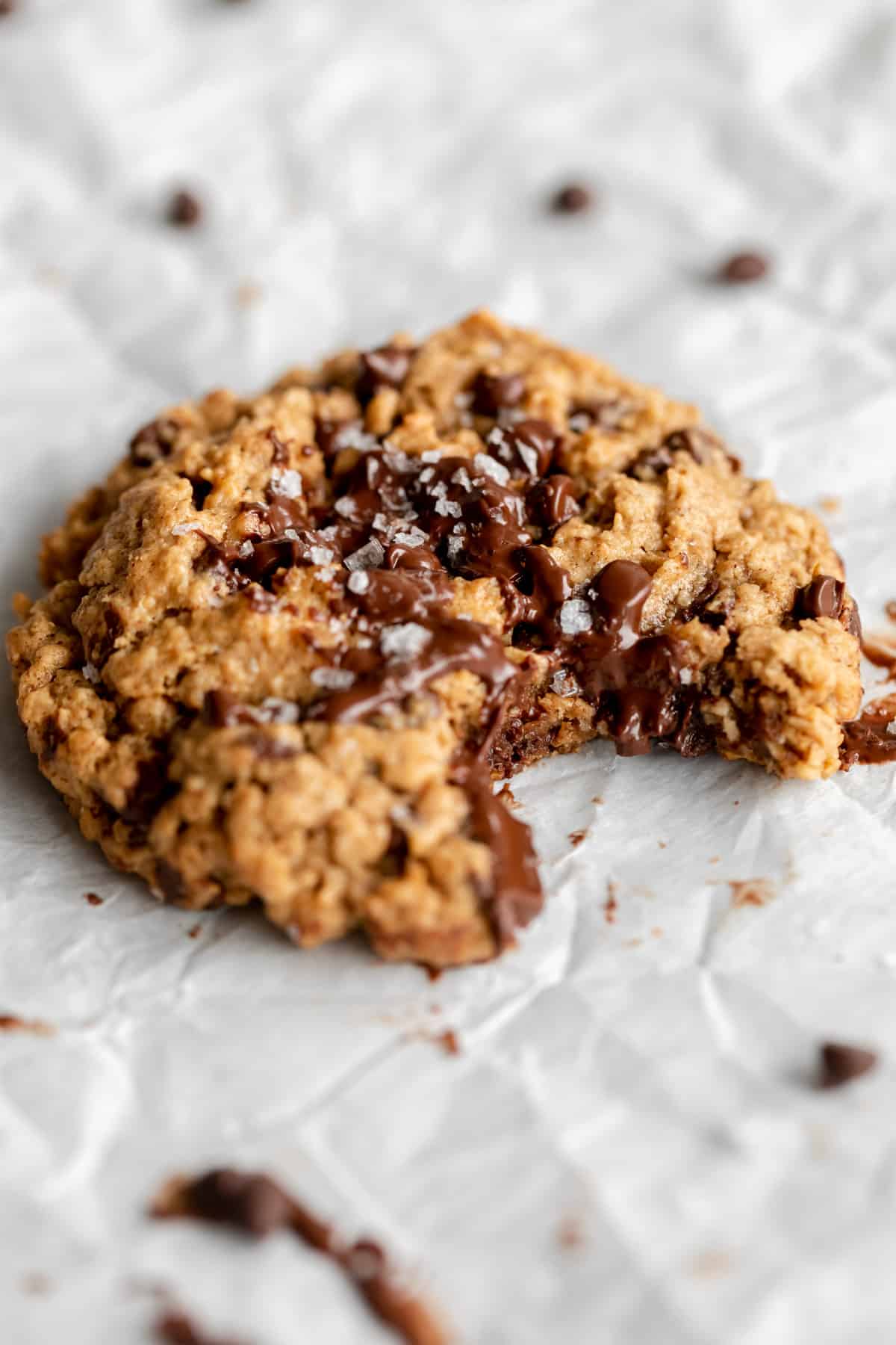 one bite taken out of the vegan gluten free oatmeal cookie with melted chocolate chips