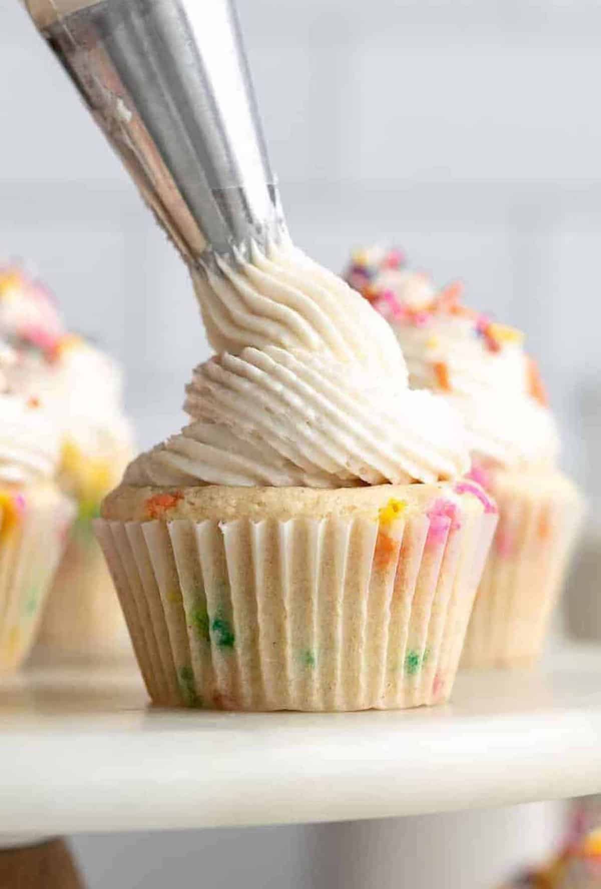 gluten free buttercream frosting piping onto a cupcake