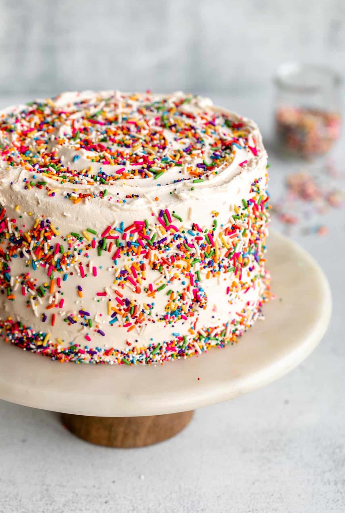 vegan gluten free vanilla cake on a cake stand with sprinkles