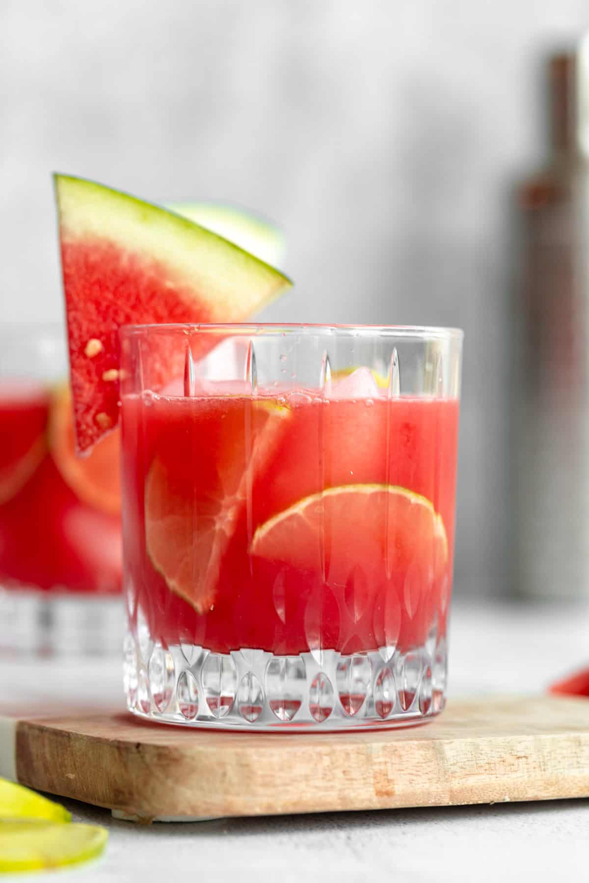 watermelon vodka cocktail in a glass with lime wedges