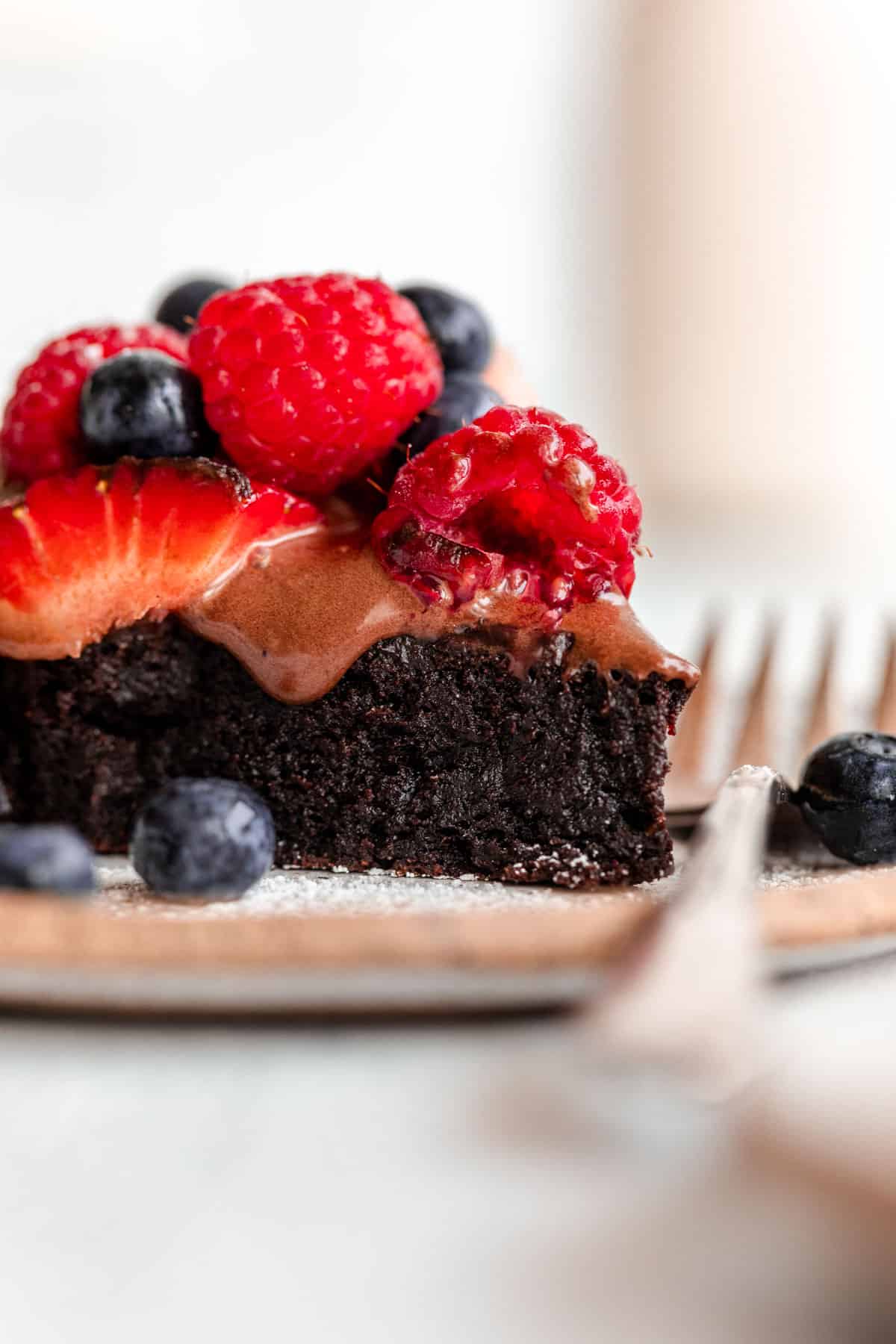 flourless chocolate cake slice on a plate with berries