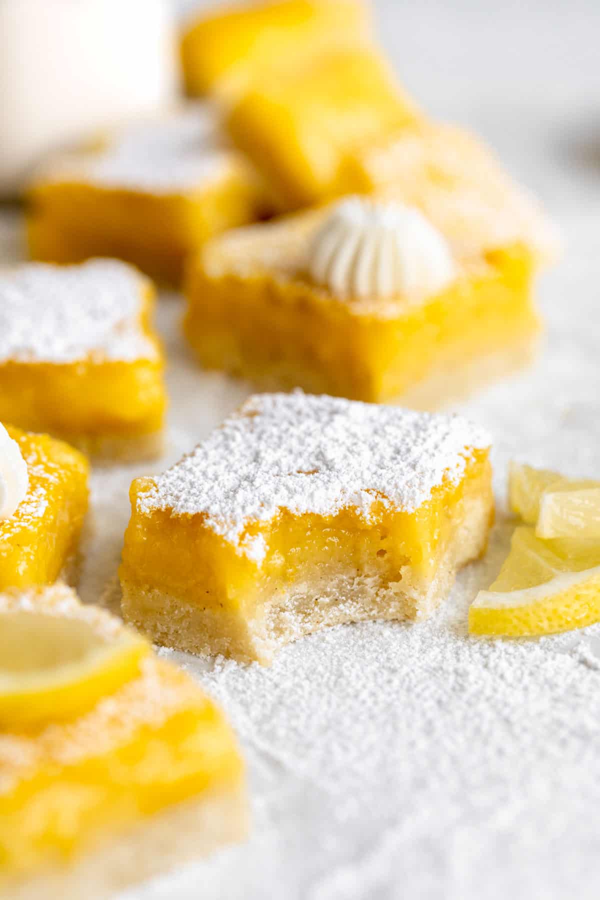 gluten free lemon bars with a bite taken out on parchment paper
