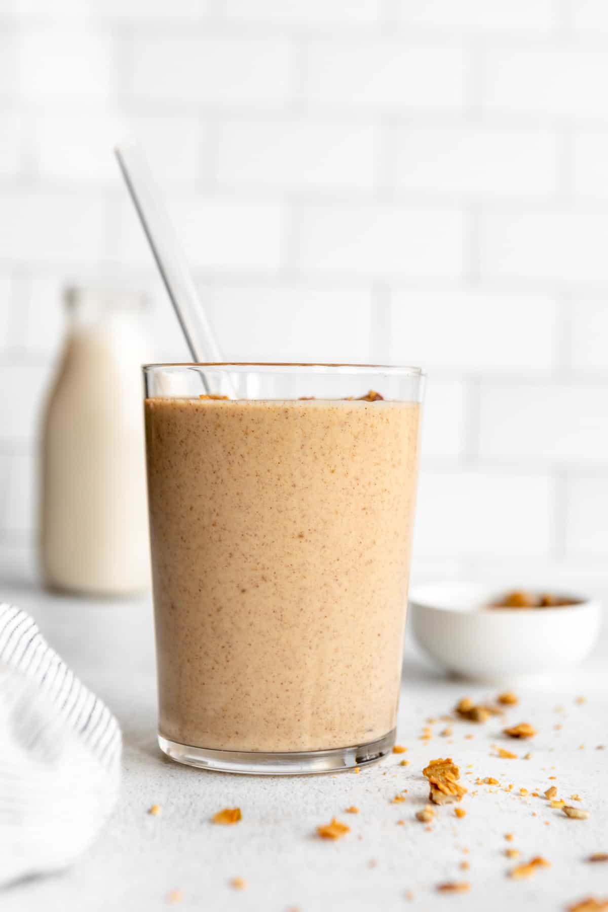 maca banana smoothie in a glass with a straw