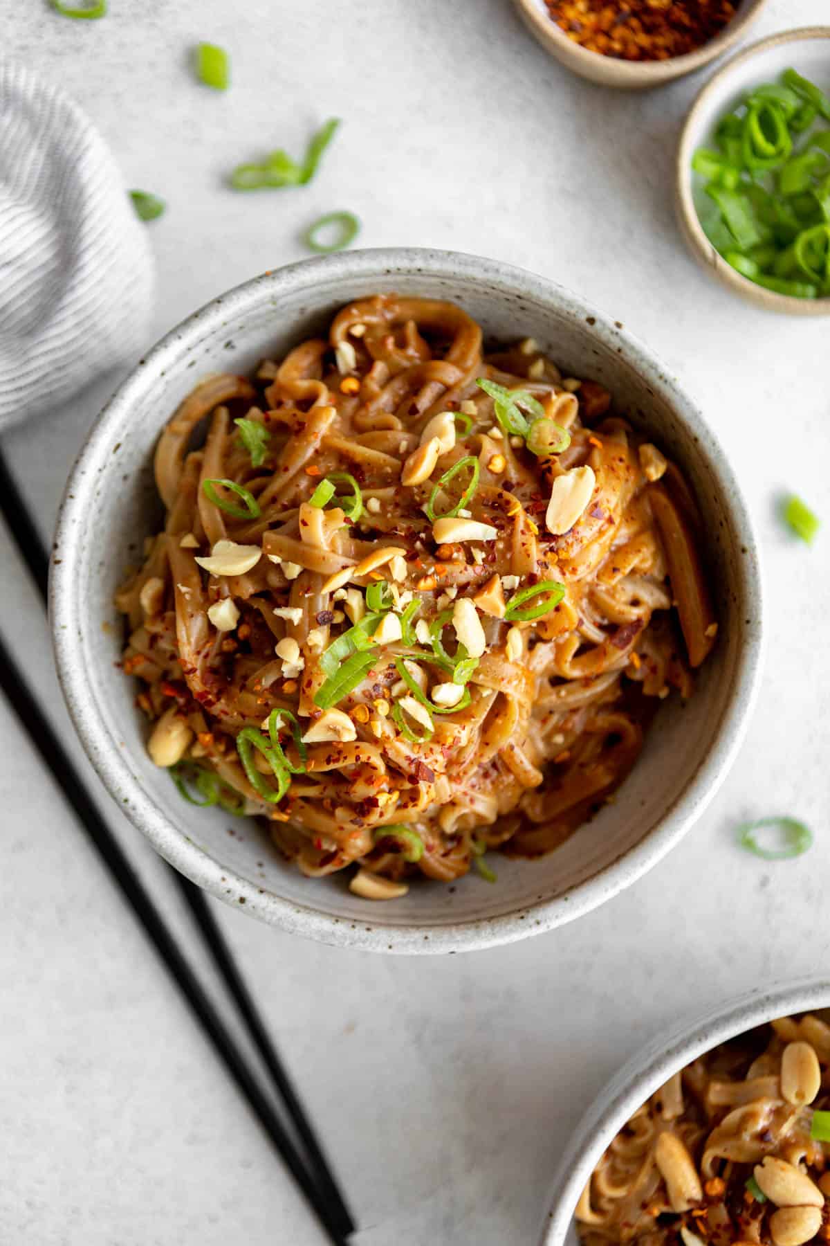 spicy peanut butter noodles in a bowl with green onion