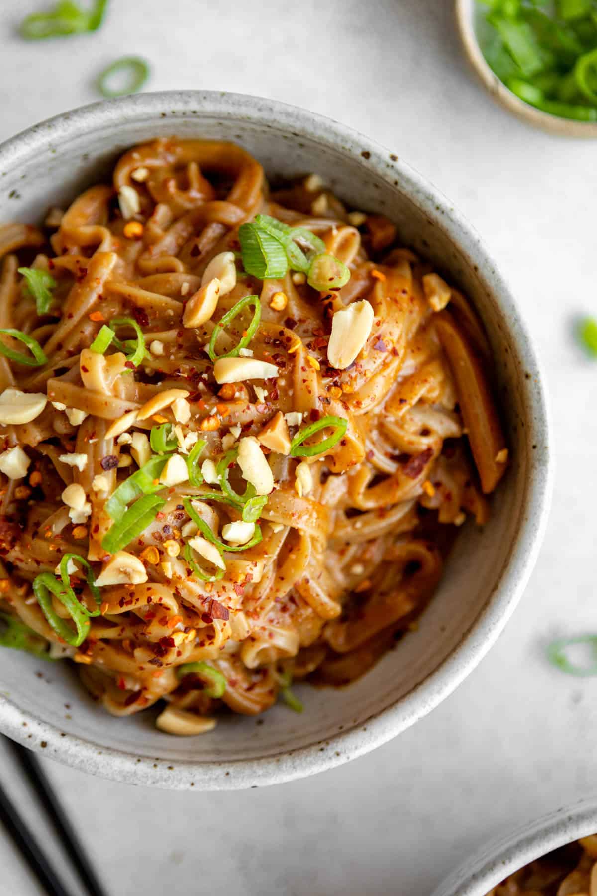 peanut butter noodles in a bowl with green onion on top