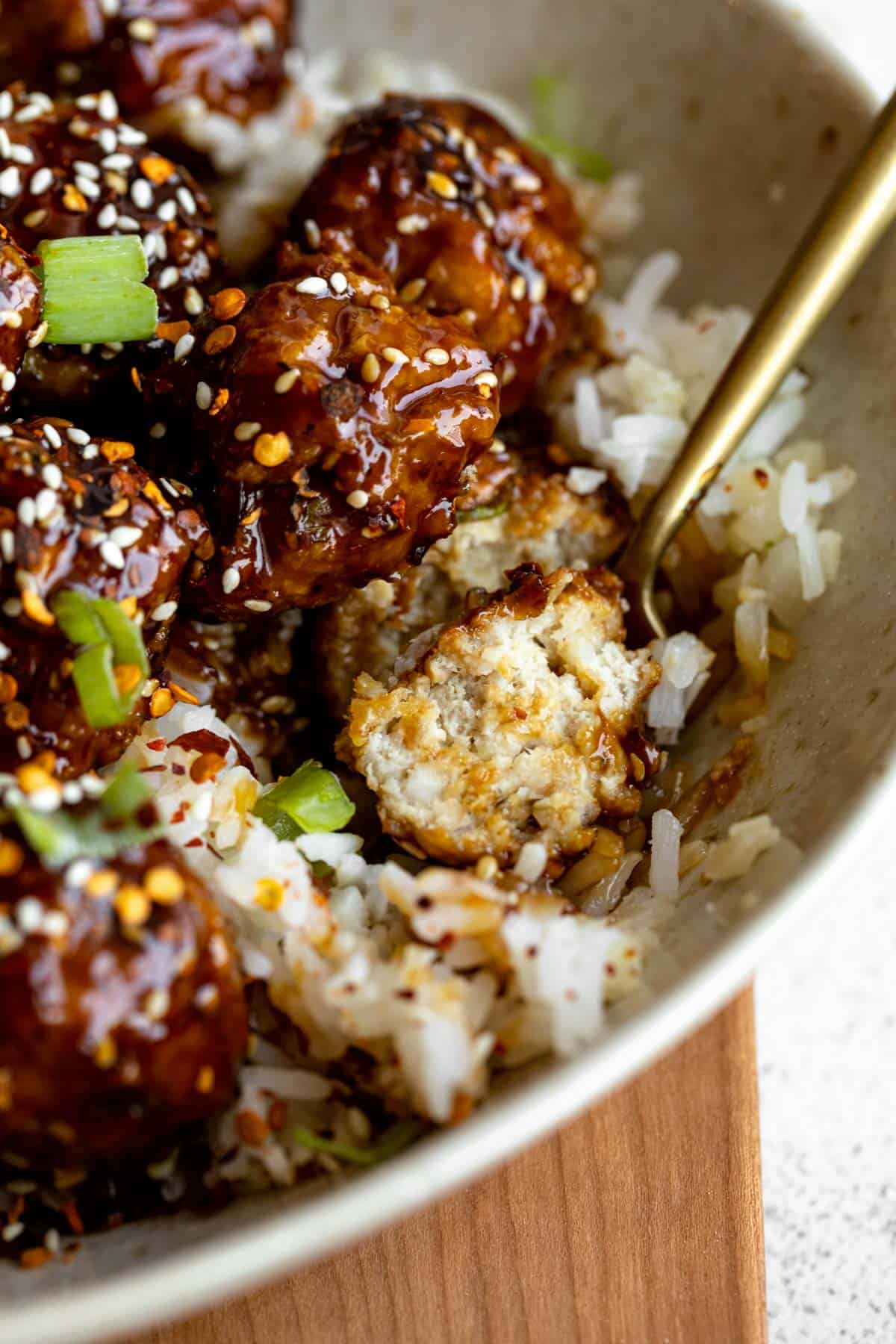 teriyaki chicken meatballs in a bowl with a fork cutting one open