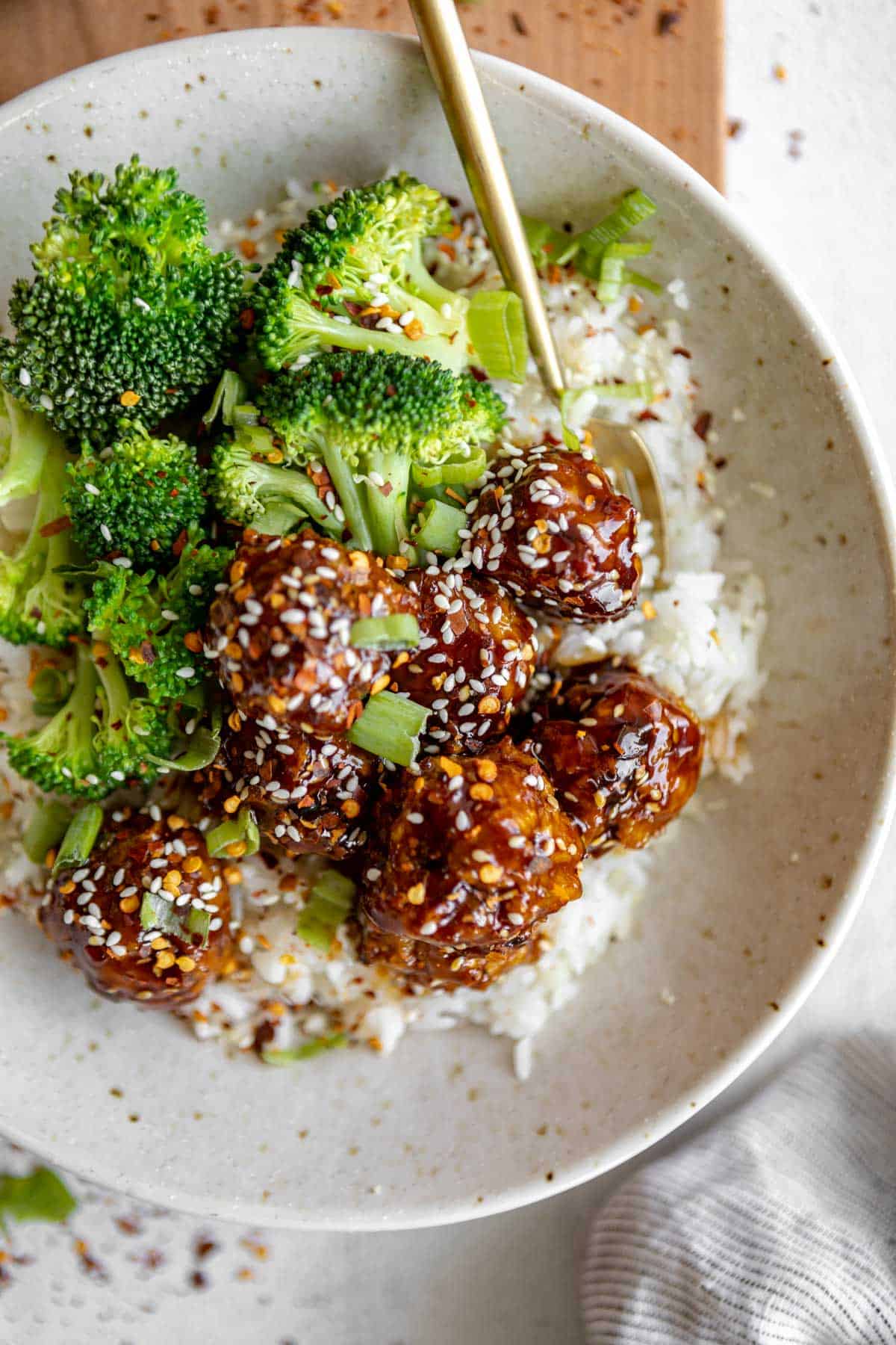 teriyaki chicken meatballs in a bowl with a fork on the side