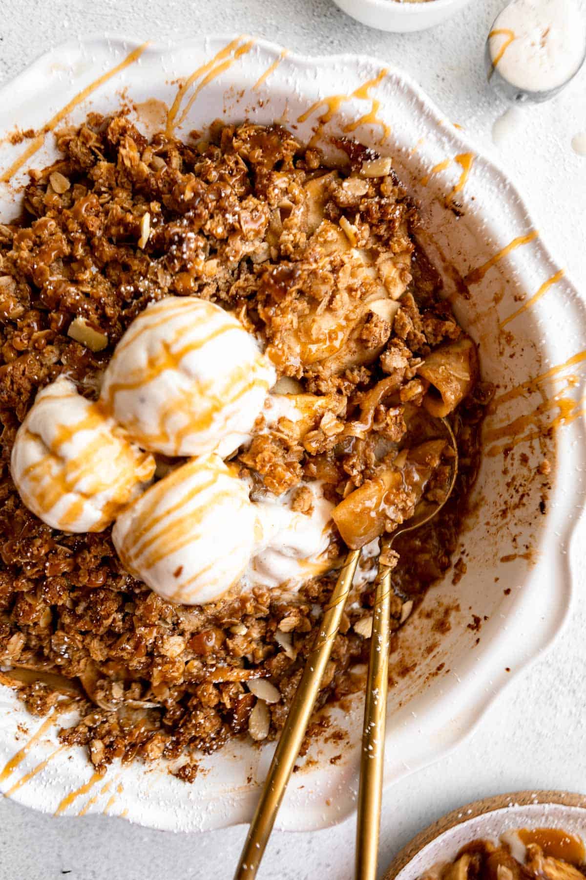 gluten free apple crisp in a pie pan with two spoons