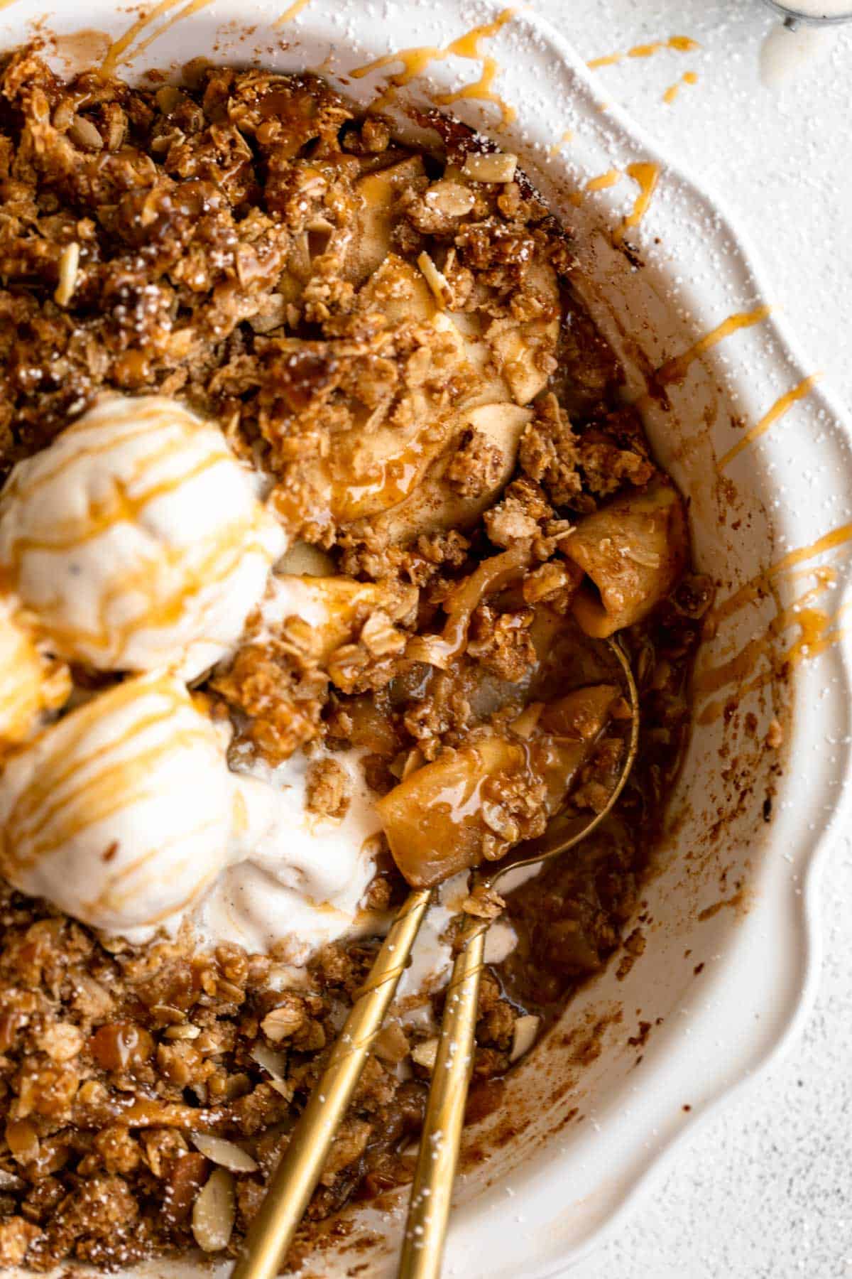 gluten free apple crisp in a pie pan with ice cream and two spoons