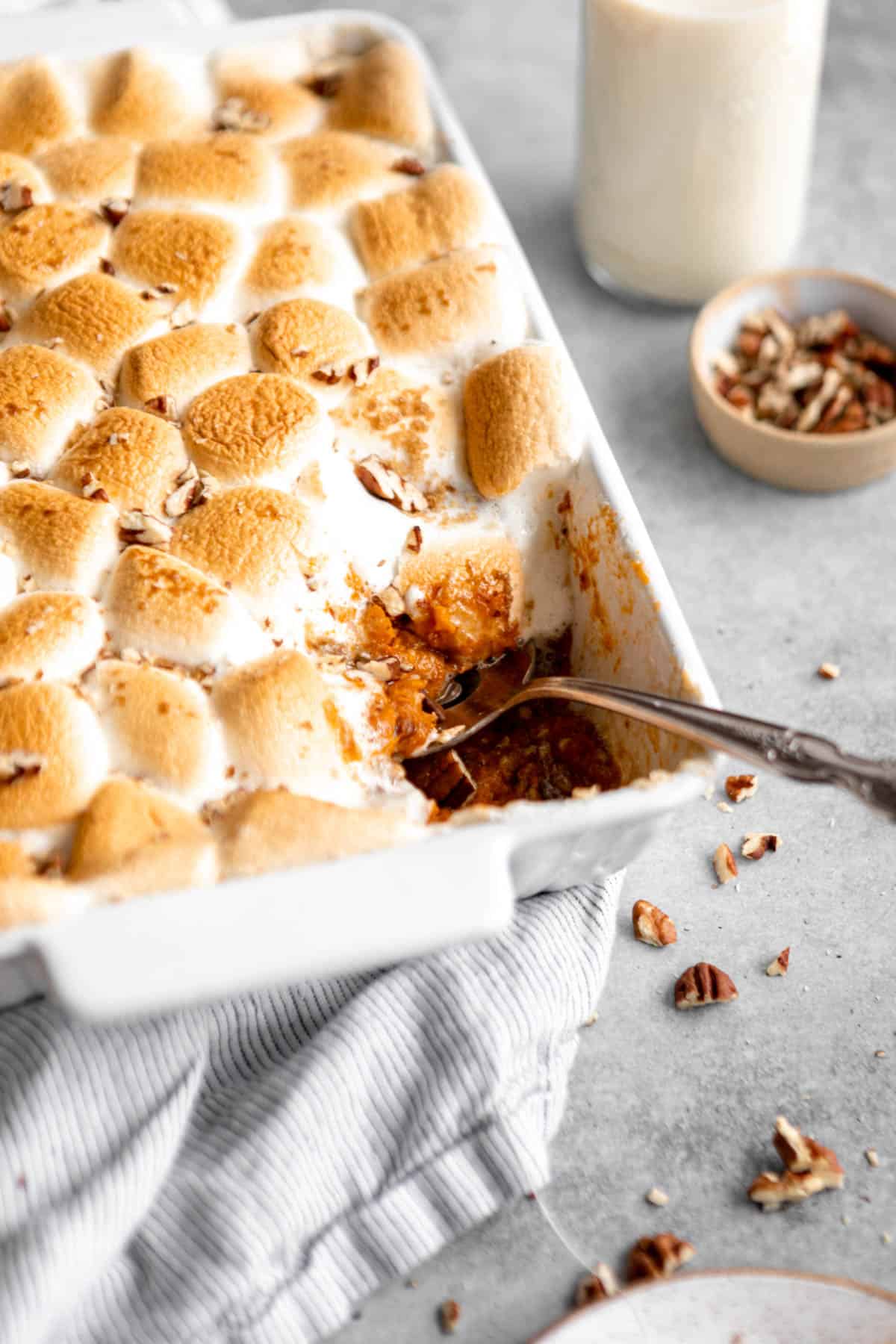 angled view of the casserole with marshmallows on top and a spoon on the side