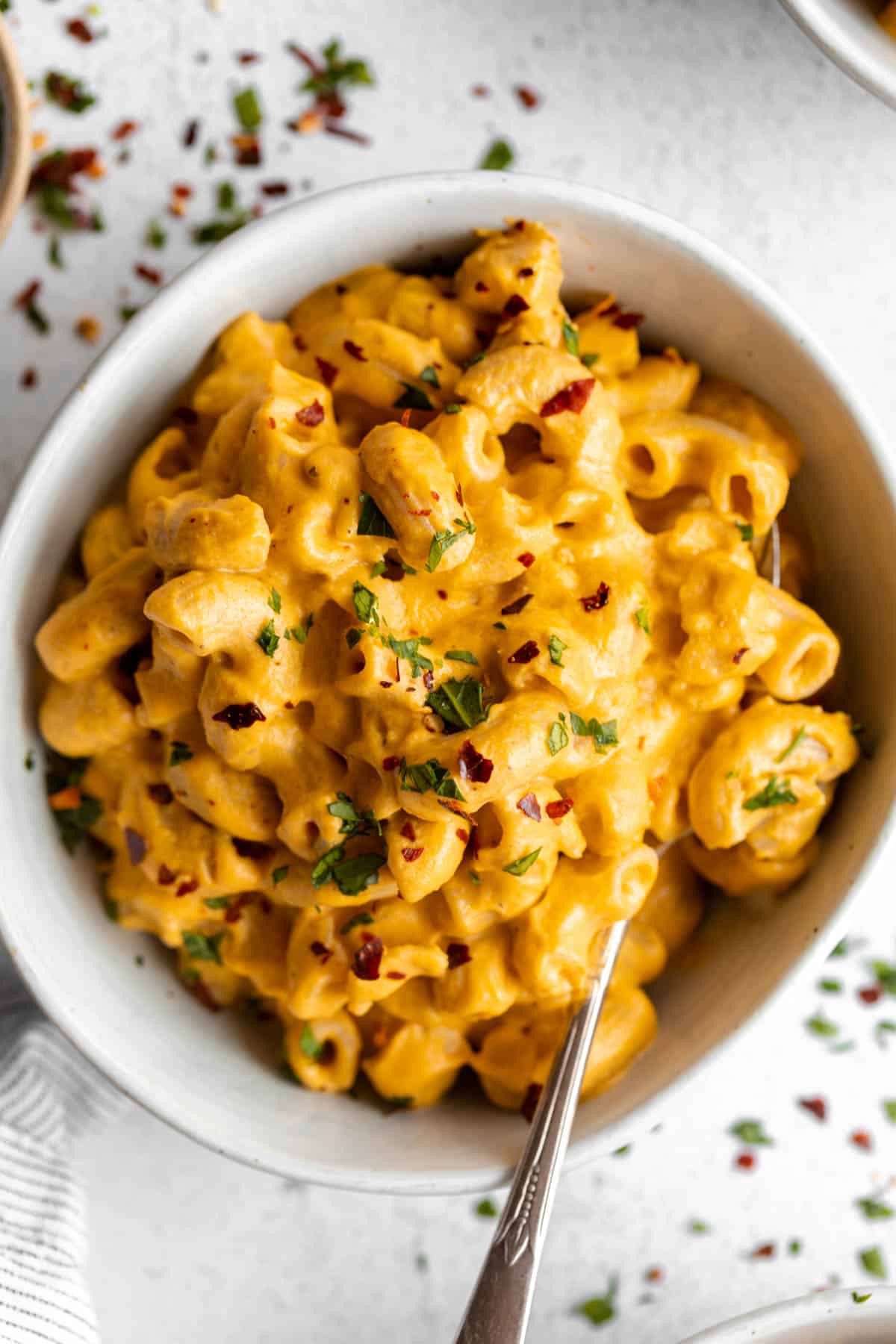 vegan sweet potato mac and cheese in a bowl with a spoon on the side