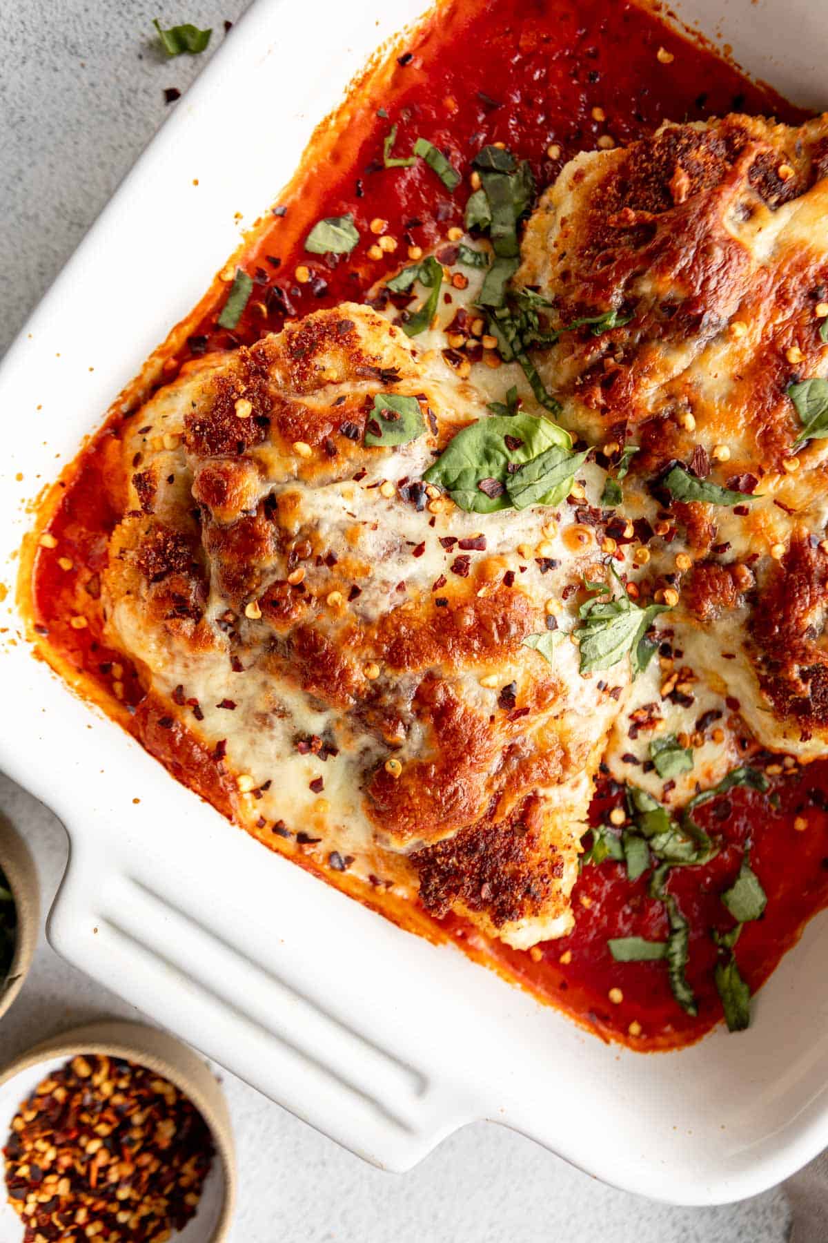 gluten free chicken parmesan in a baking dish with mozzarella and basil