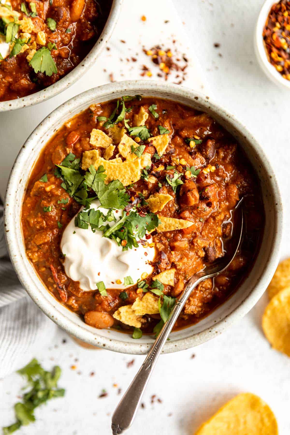 gluten free beef chili in a bowl with a spoon on the side