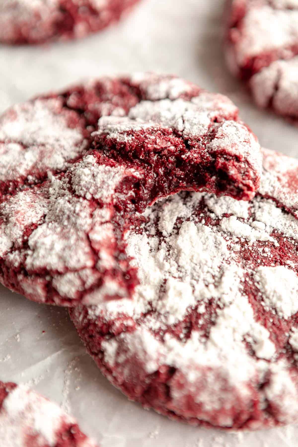 one bite taken out of the gluten free red velvet crinkle cookie to show fudgy texture