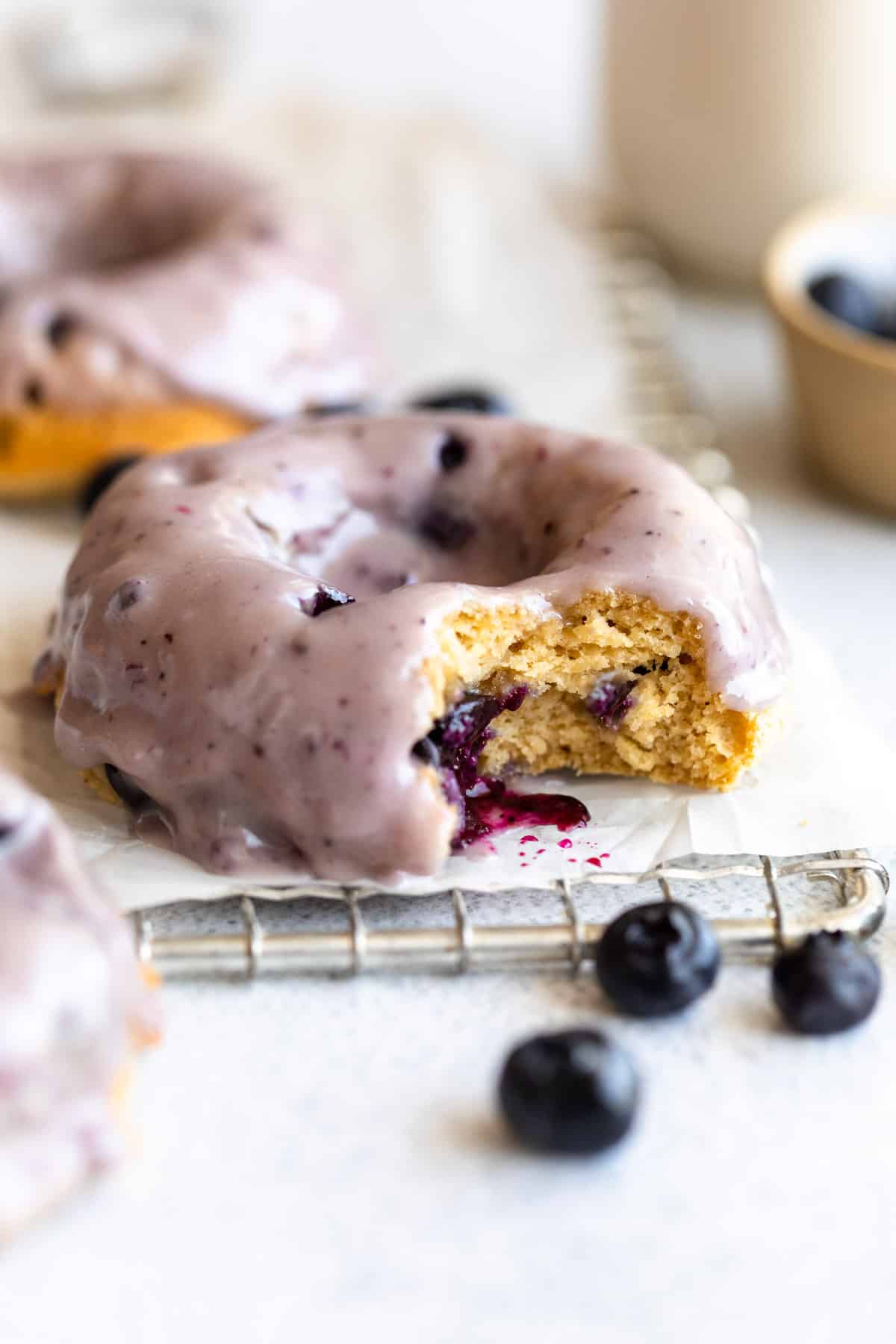 blueberry protein donuts with a bite taken out on a wire rack