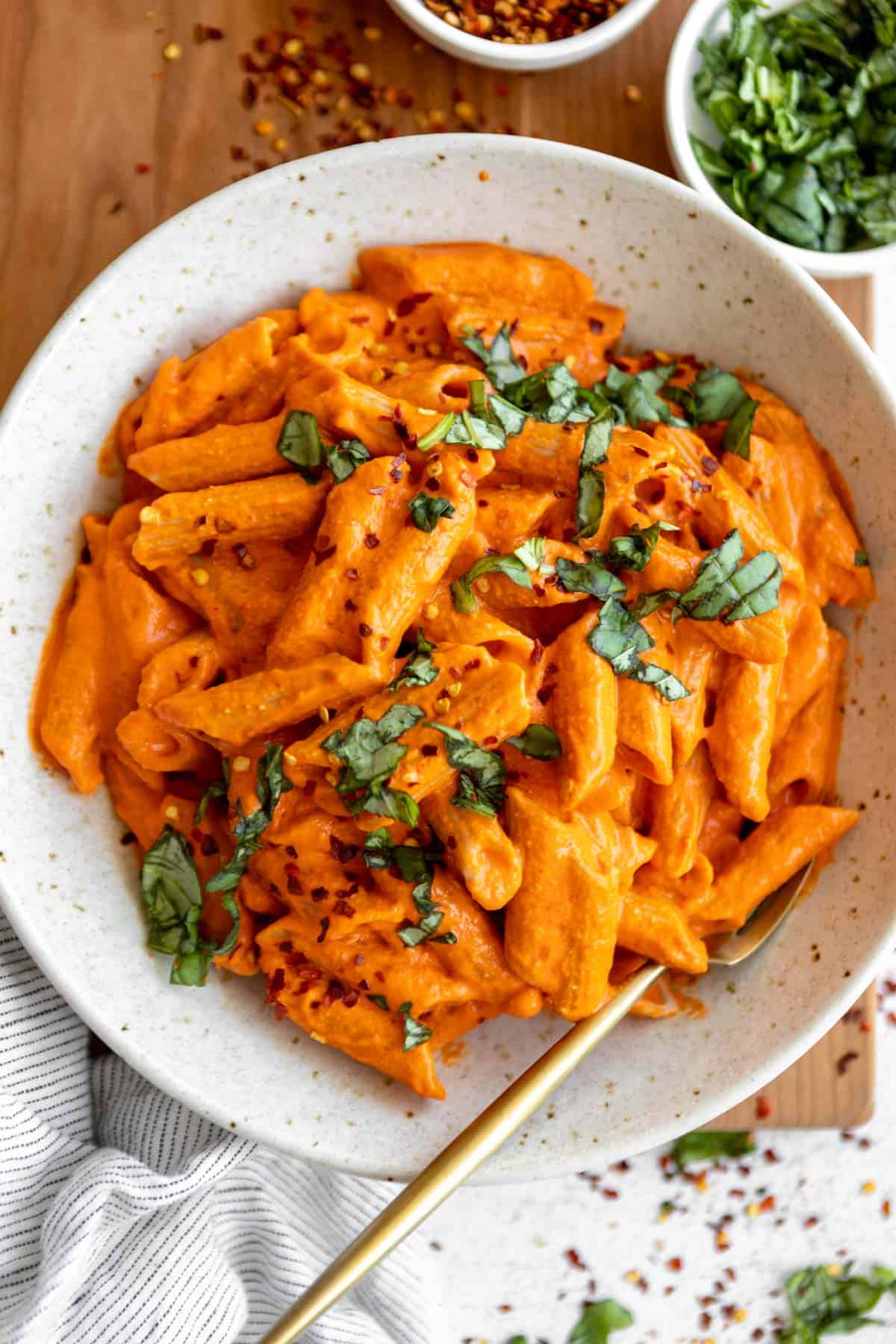 spicy vodka pasta with penne in a bowl with basil and roasted red pepper flakes