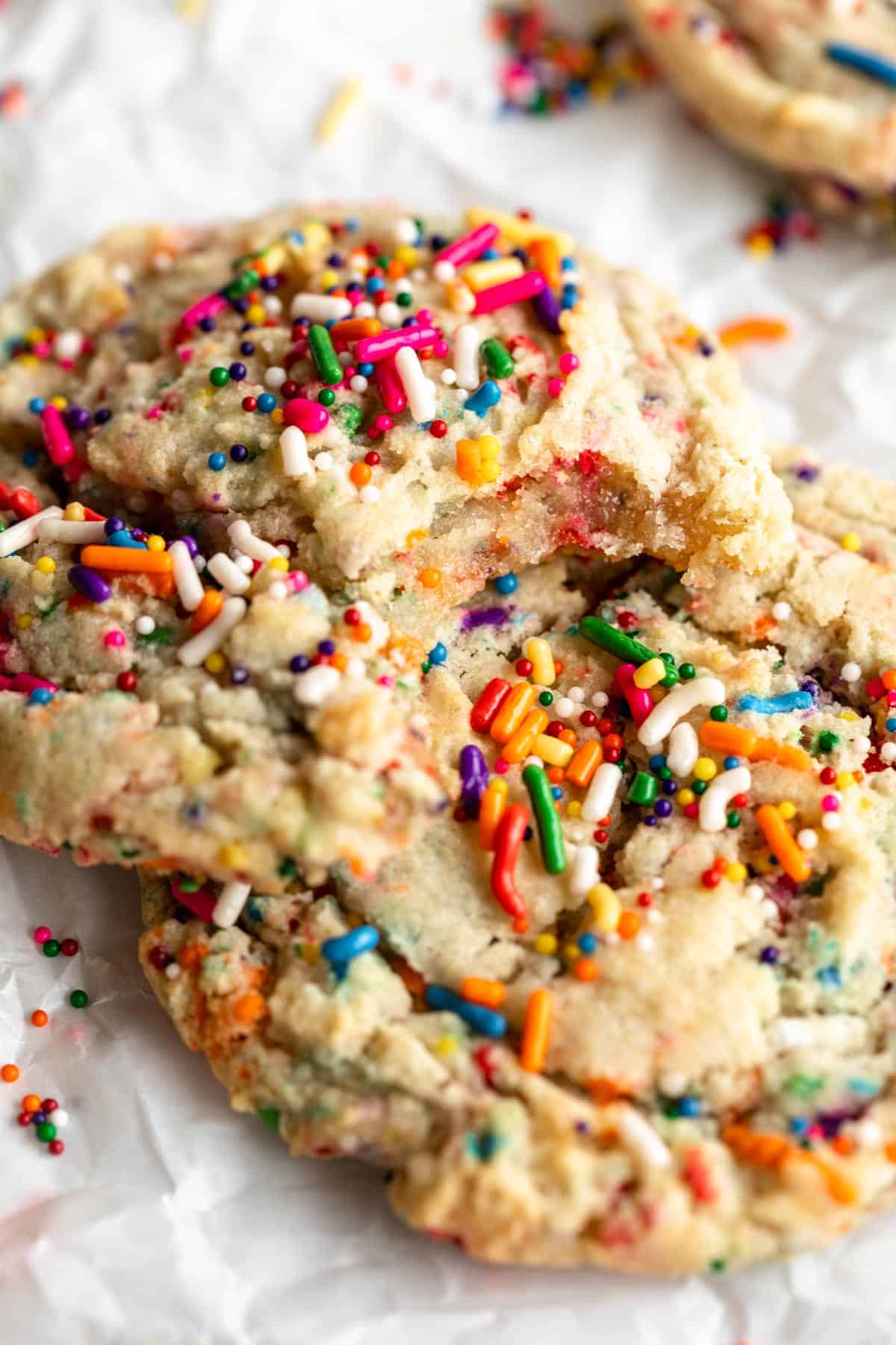 vegan funfetti sugar cookies with a bite taken out on parchment paper