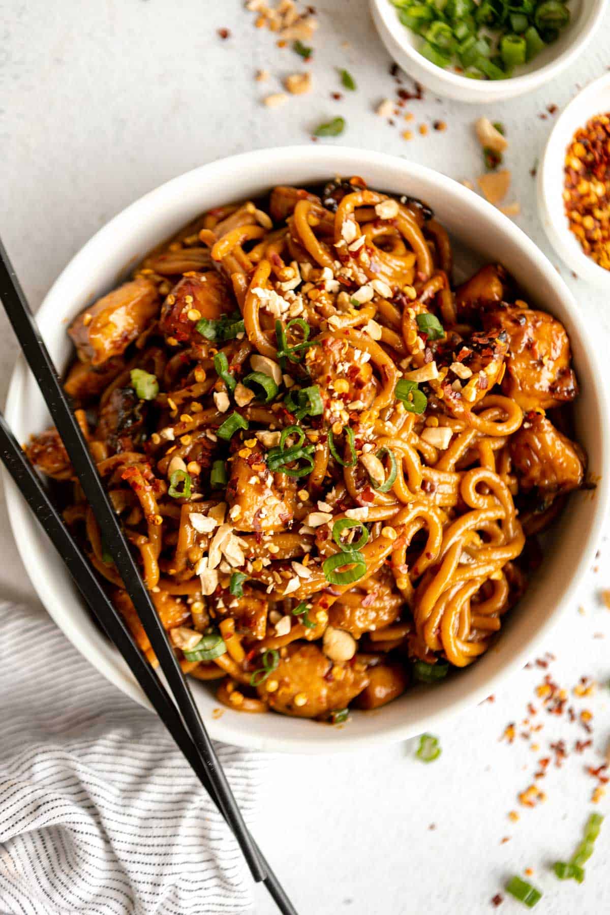 kung pao chicken noodles in a bowl with peanuts on top