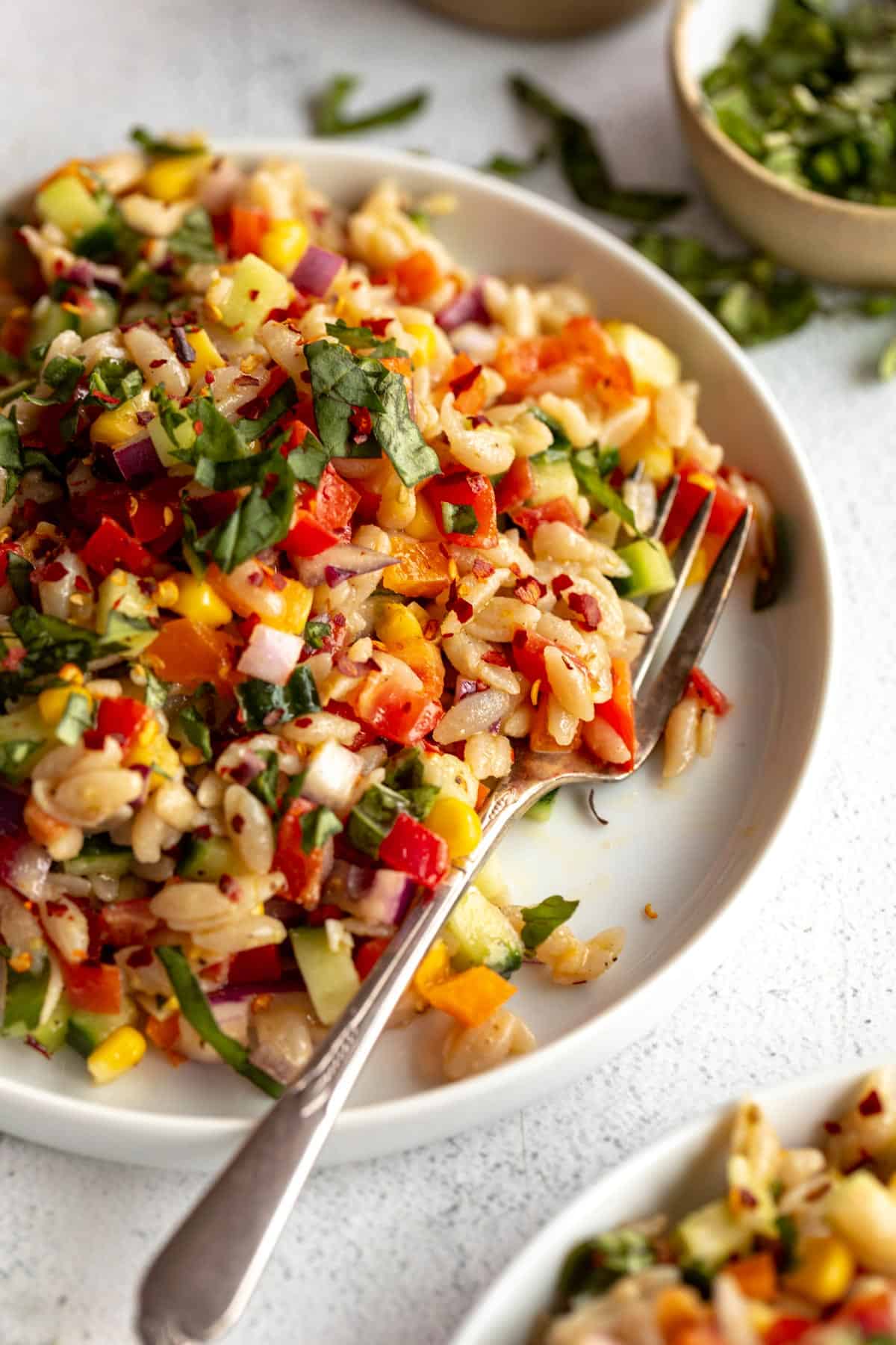 chopped vegetable and orzo salad on a plate with a fork