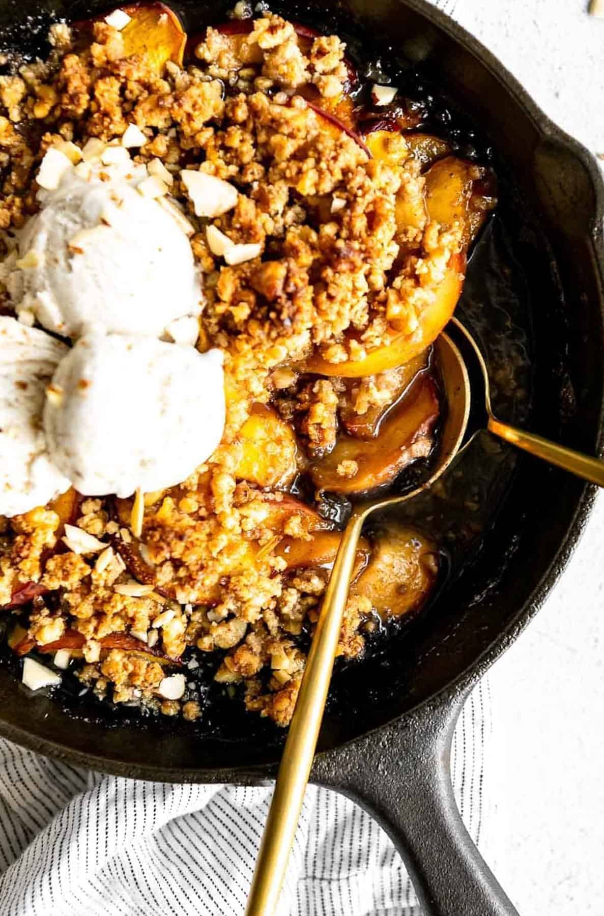 gluten free peach crisp in a pan with ice cream on top