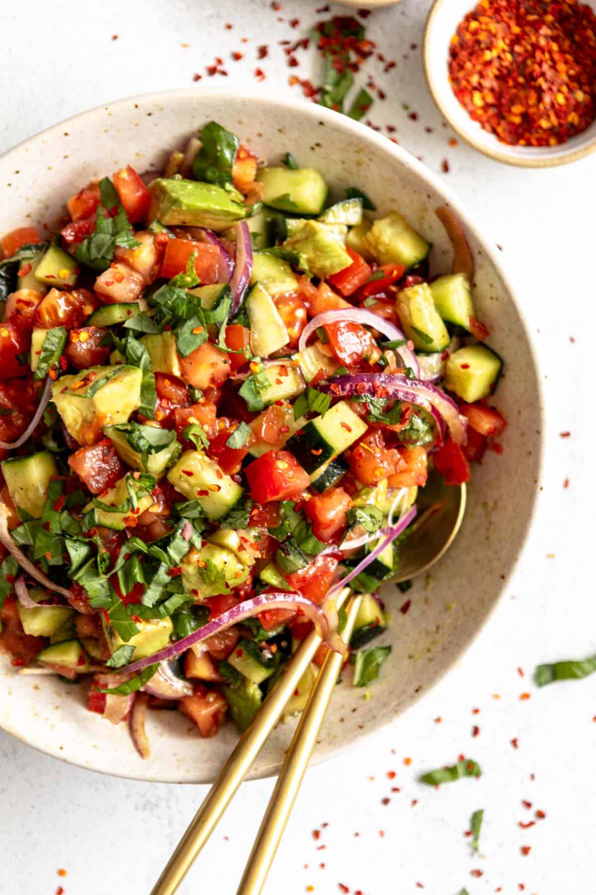 tomato cucumber avocado salad with a spoon on the side