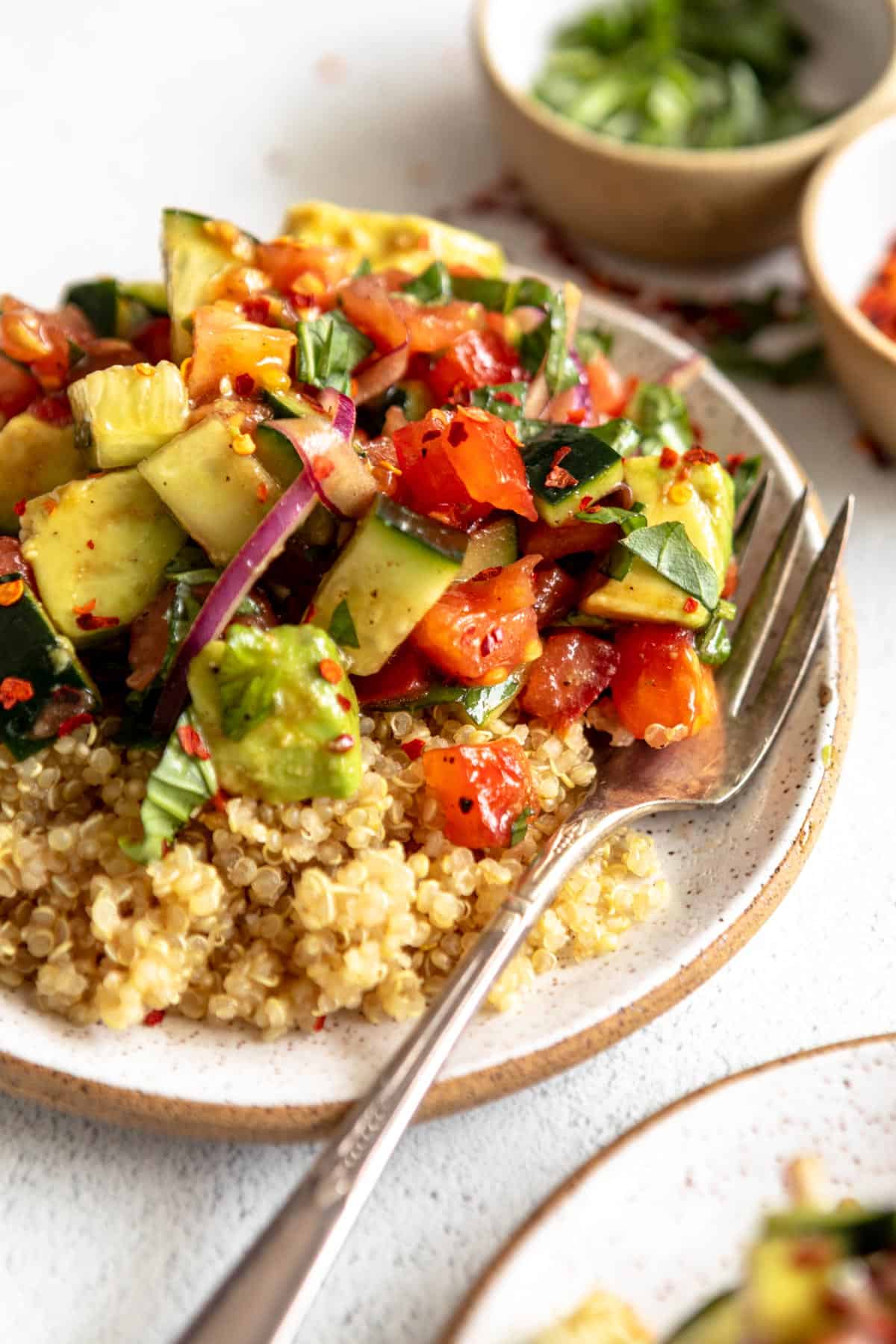 angled view of the cucumber tomato salad served over quinoa with basil