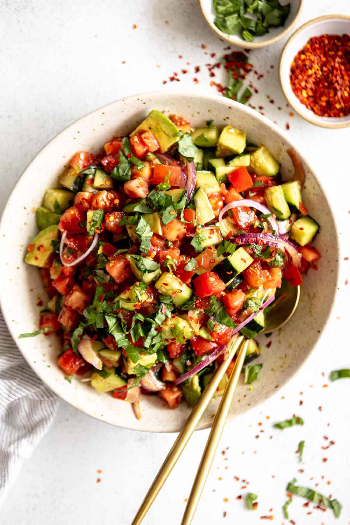 tomato cucumber salad with two spoons on the side