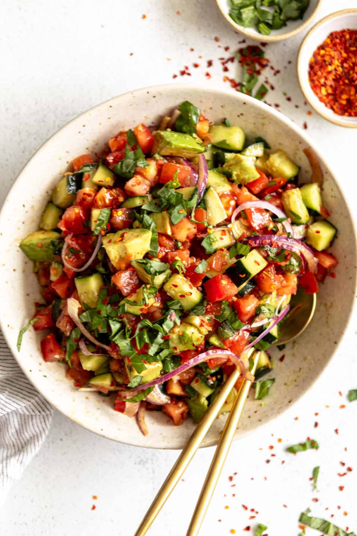 tomato cucumber salad in a bowl with red onion and basil