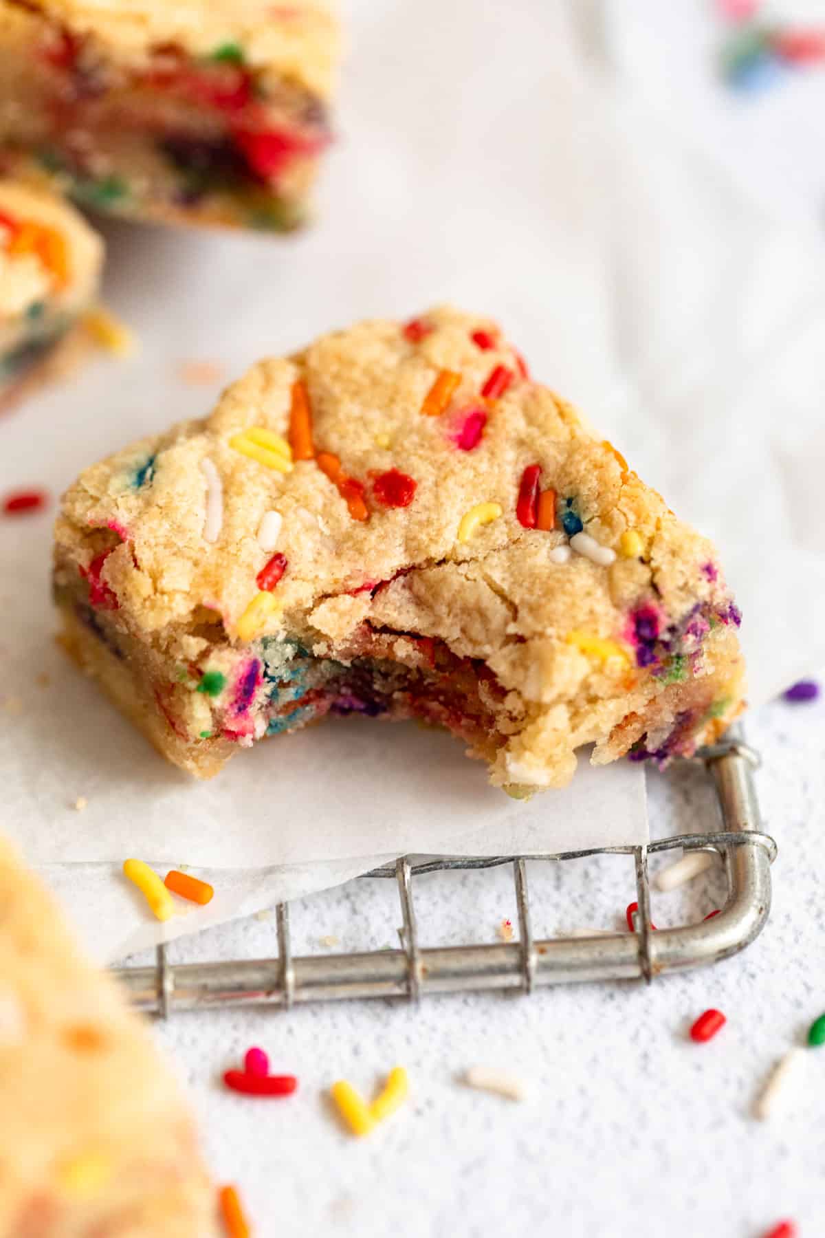 vegan funfetti blondies with a bite taken out on parchment paper