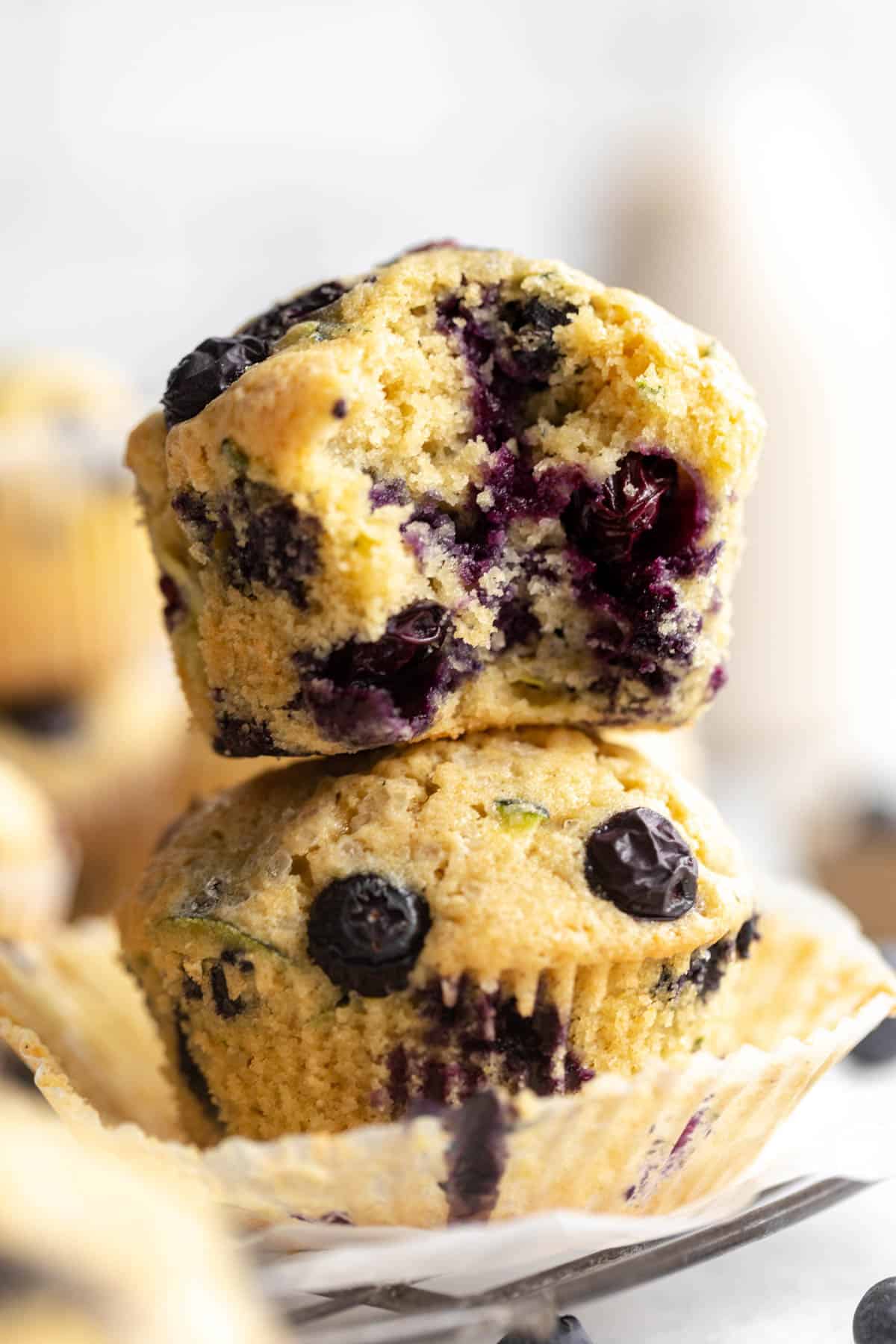 two gluten free zucchini muffins with blueberries stacked on each other
