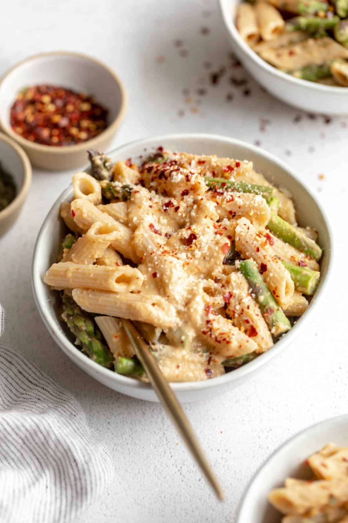 vegan lemon white bean pasta with asparagus and a fork on the side