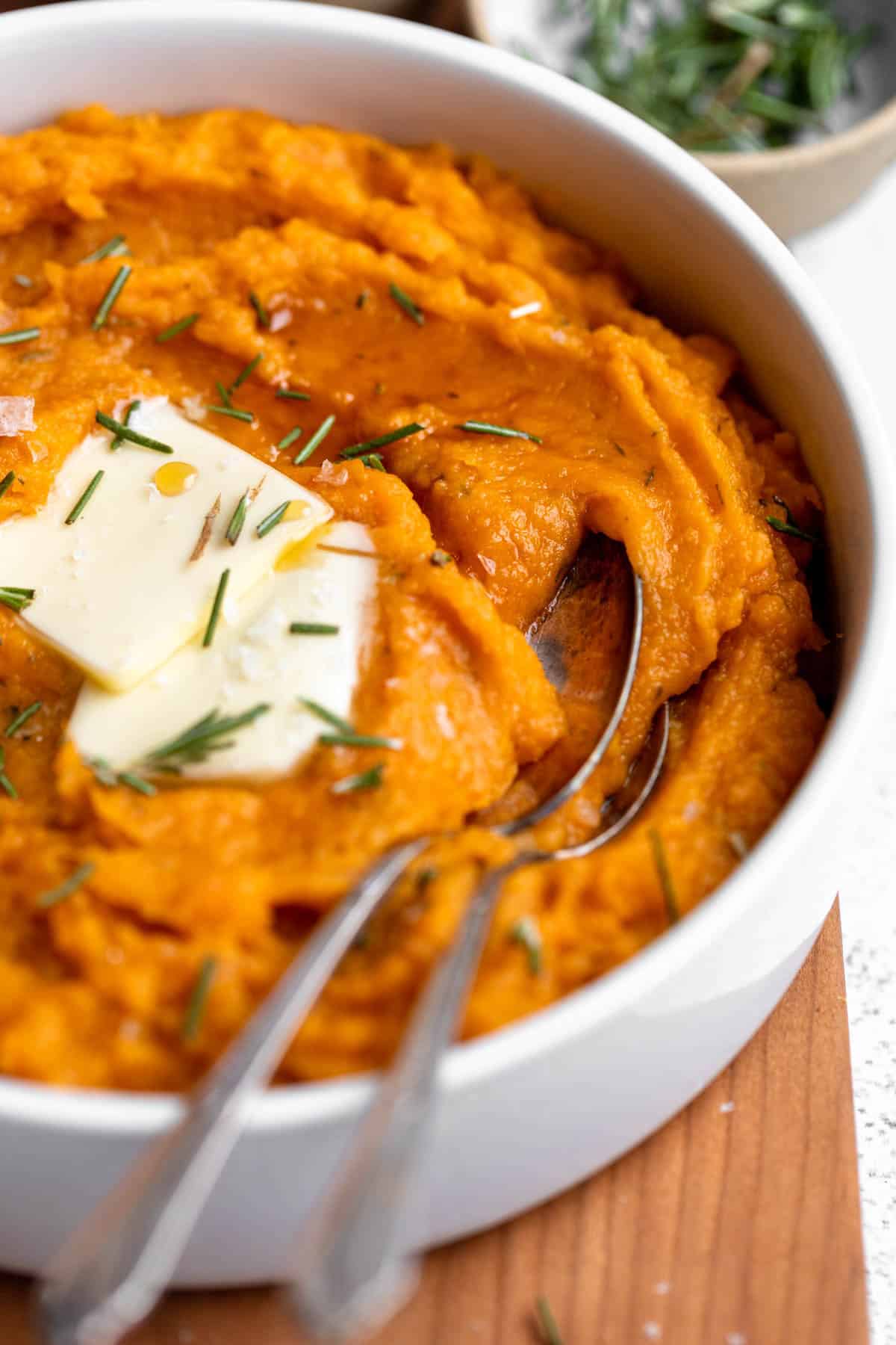 angled view of the mashed sweet potatoes in a bowl with two spoons