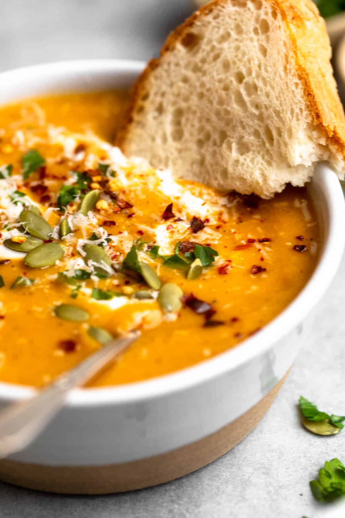 angled view of the roasted vegetable soup with bread on the side
