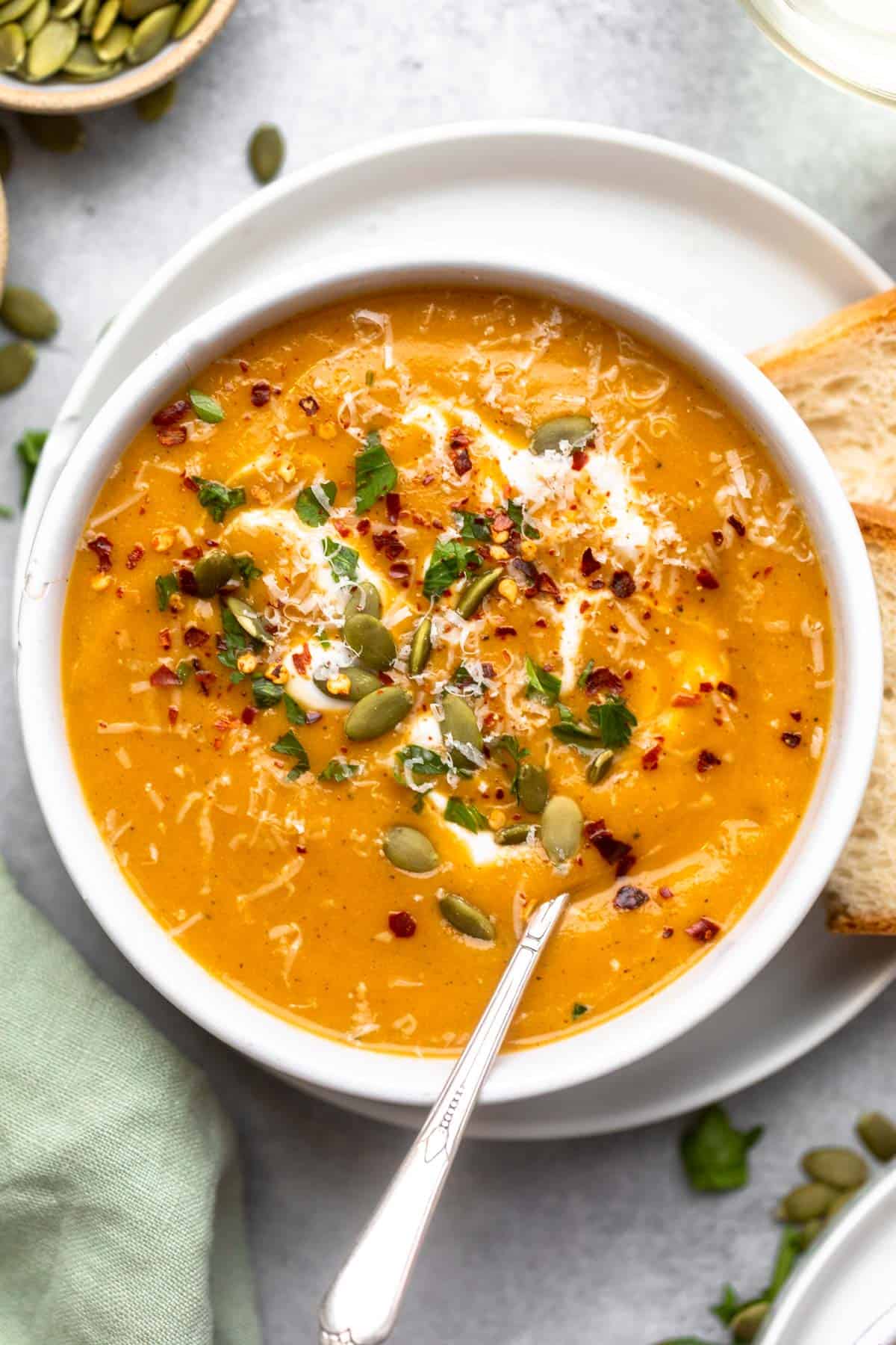 roasted vegetable soup in a bowl with pumpkin seeds and bread