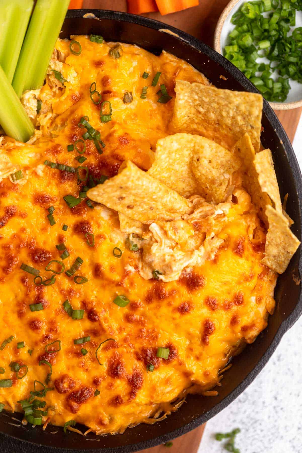 gluten free buffalo chicken dip with chips on the side in a cast iron pan