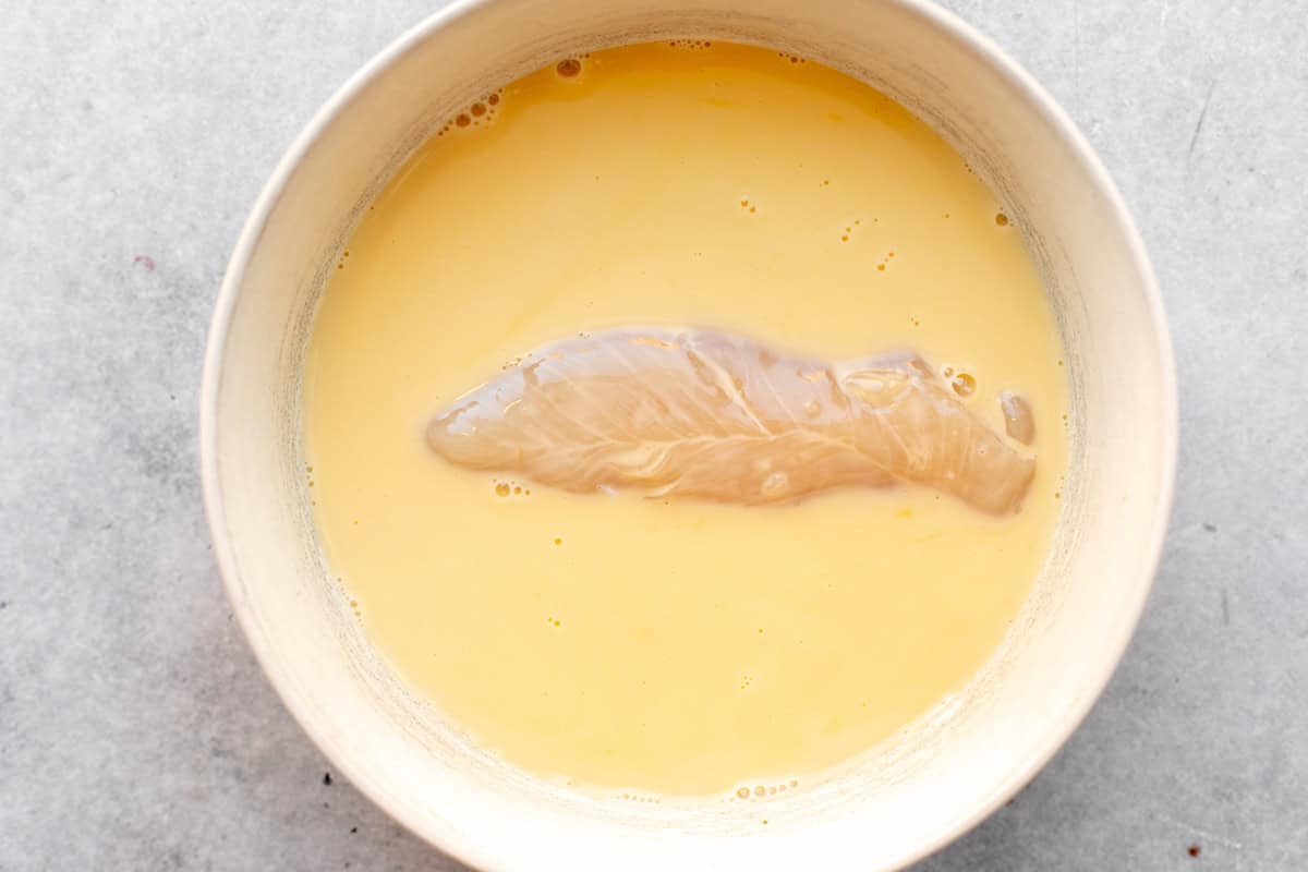 chicken tender in a bowl with the egg wash