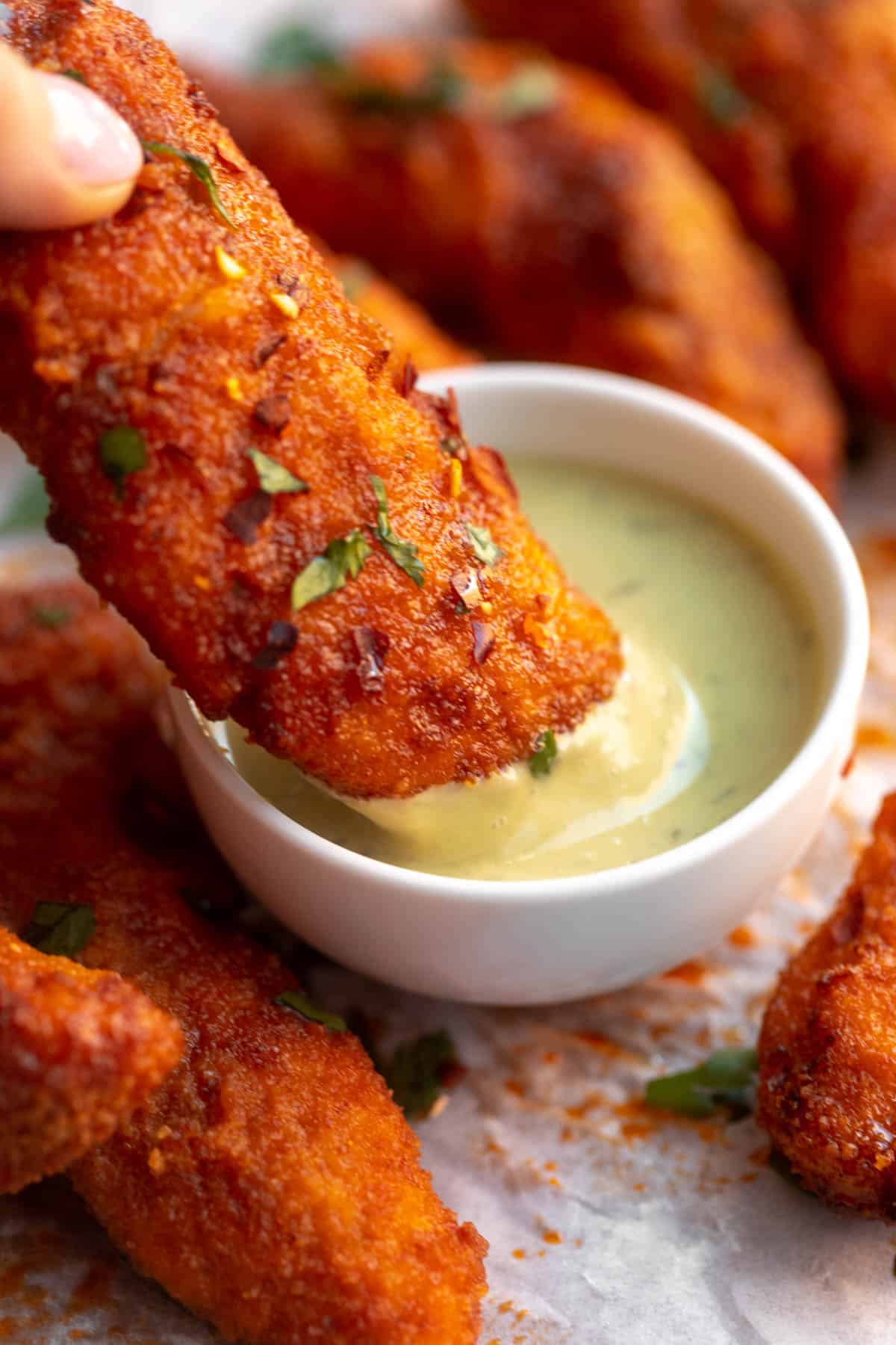 dipping the gluten free buffalo chicken tender in a sauce