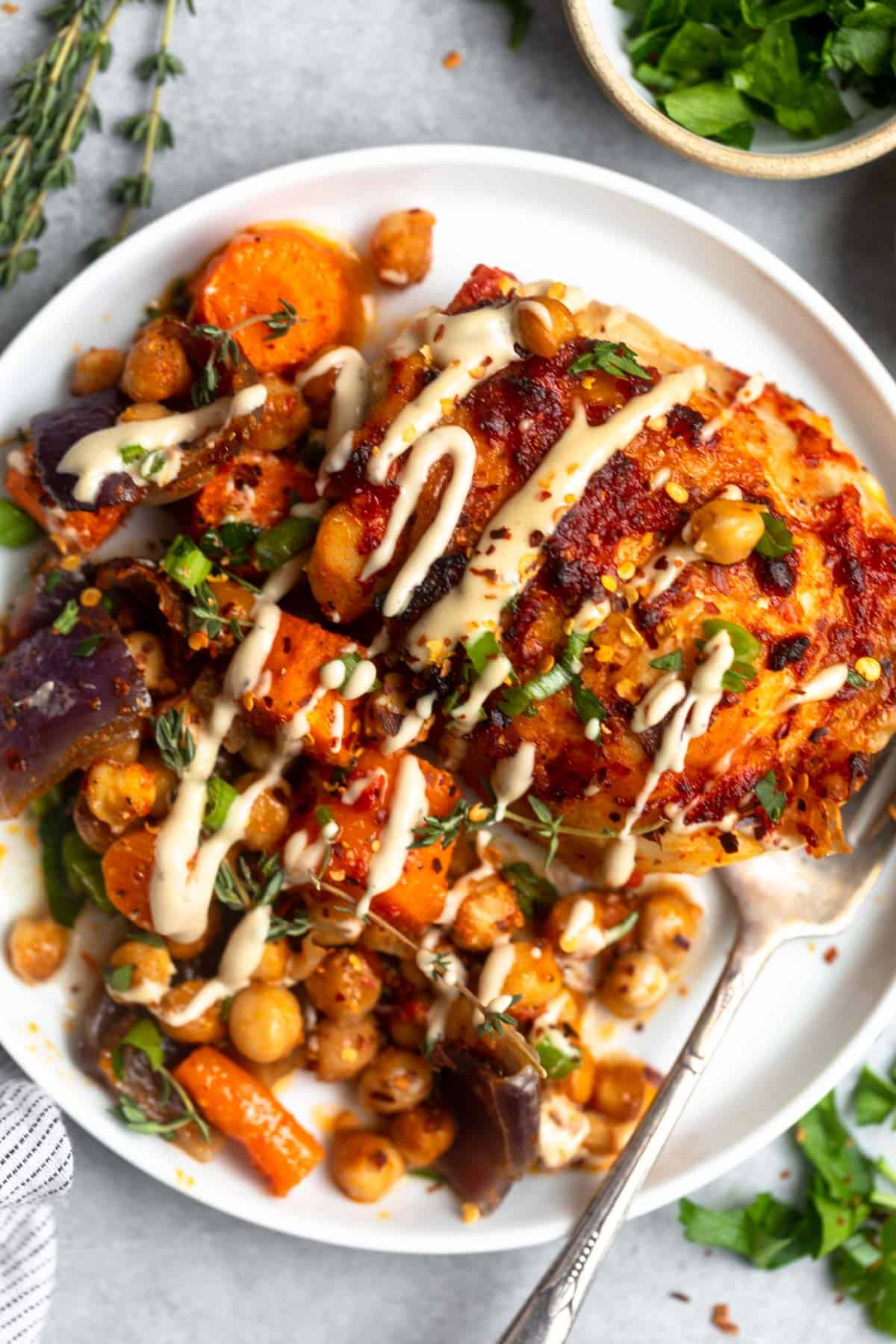 sheet pan chicken on a plate with veggies and dressing