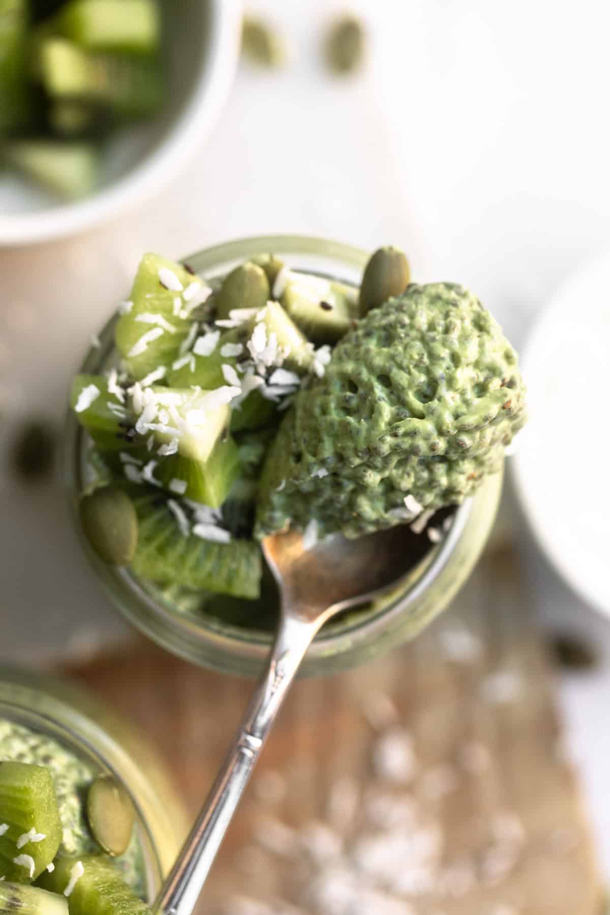 spoon taking a bite of the matcha chia pudding in a jar