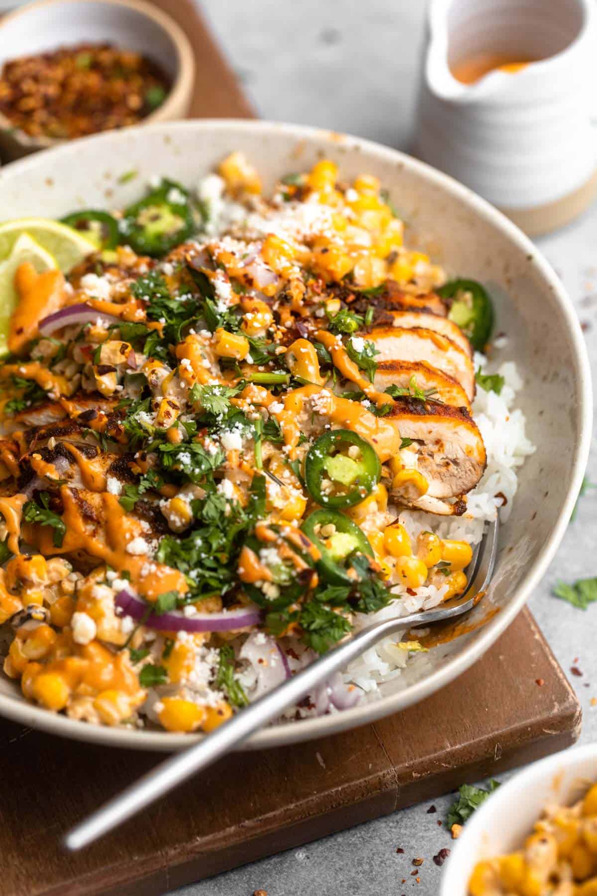 angled view of the street corn chicken rice bowl with crema on top