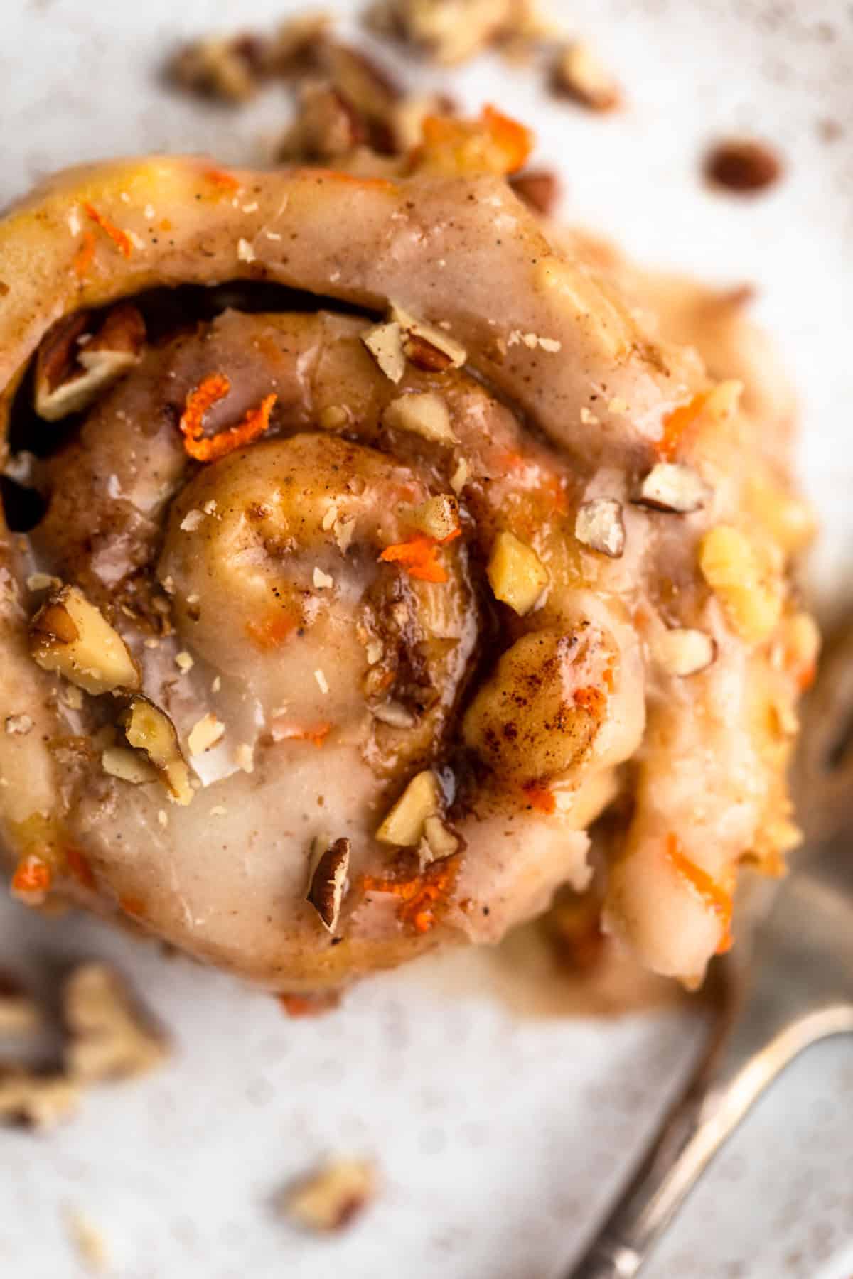 one gluten free carrot cake cinnamon roll on a plate with a fork