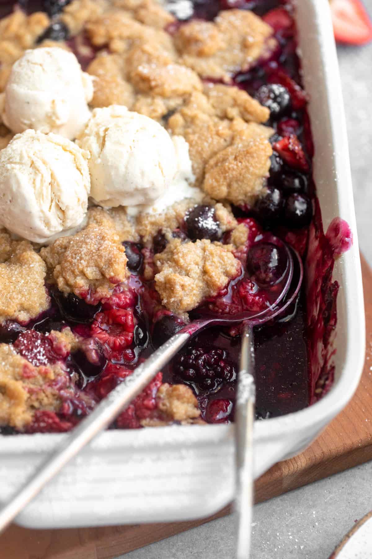 gluten free berry crumble in a baking dish with ice cream on top
