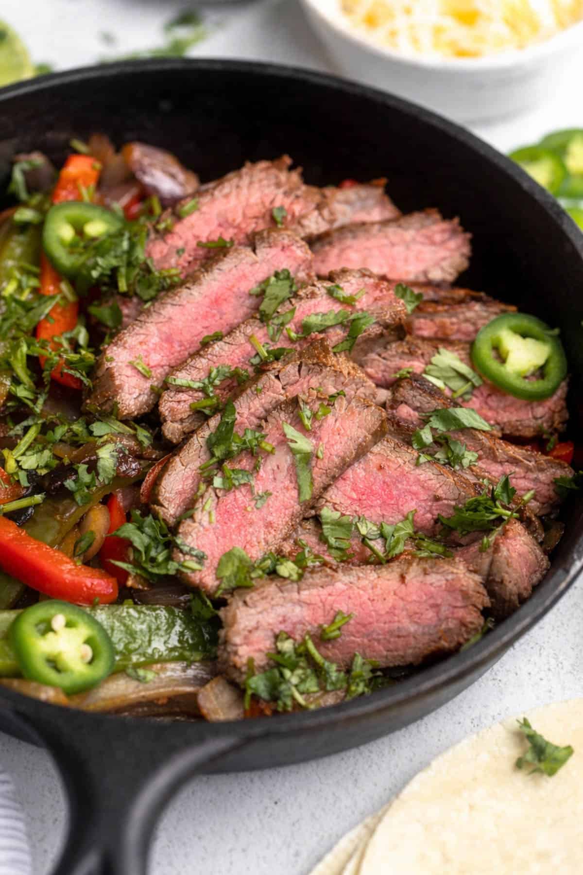 angled view of the gluten free steak fajitas in a skillet with veggies