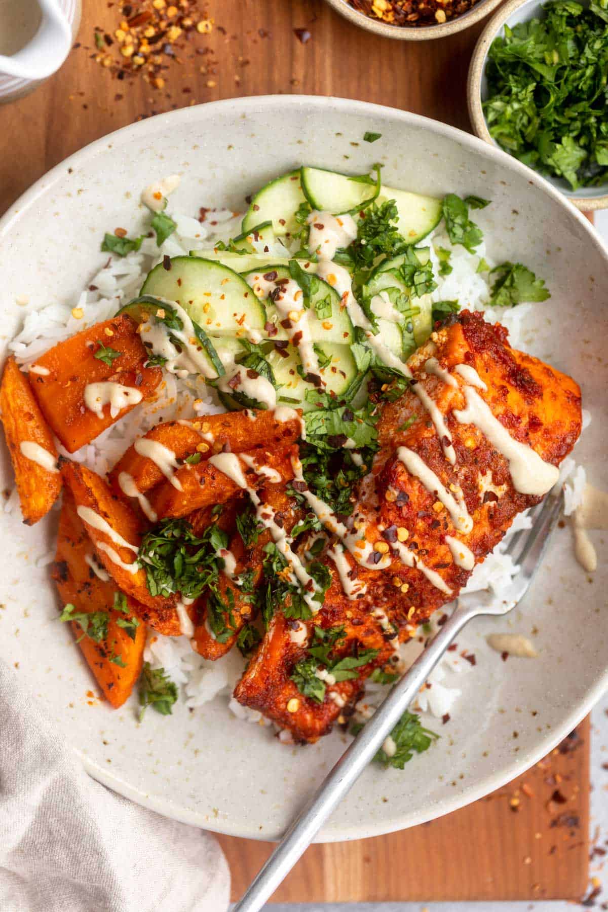roasted harissa salmon in a bowl with carrots, cucumber and rice