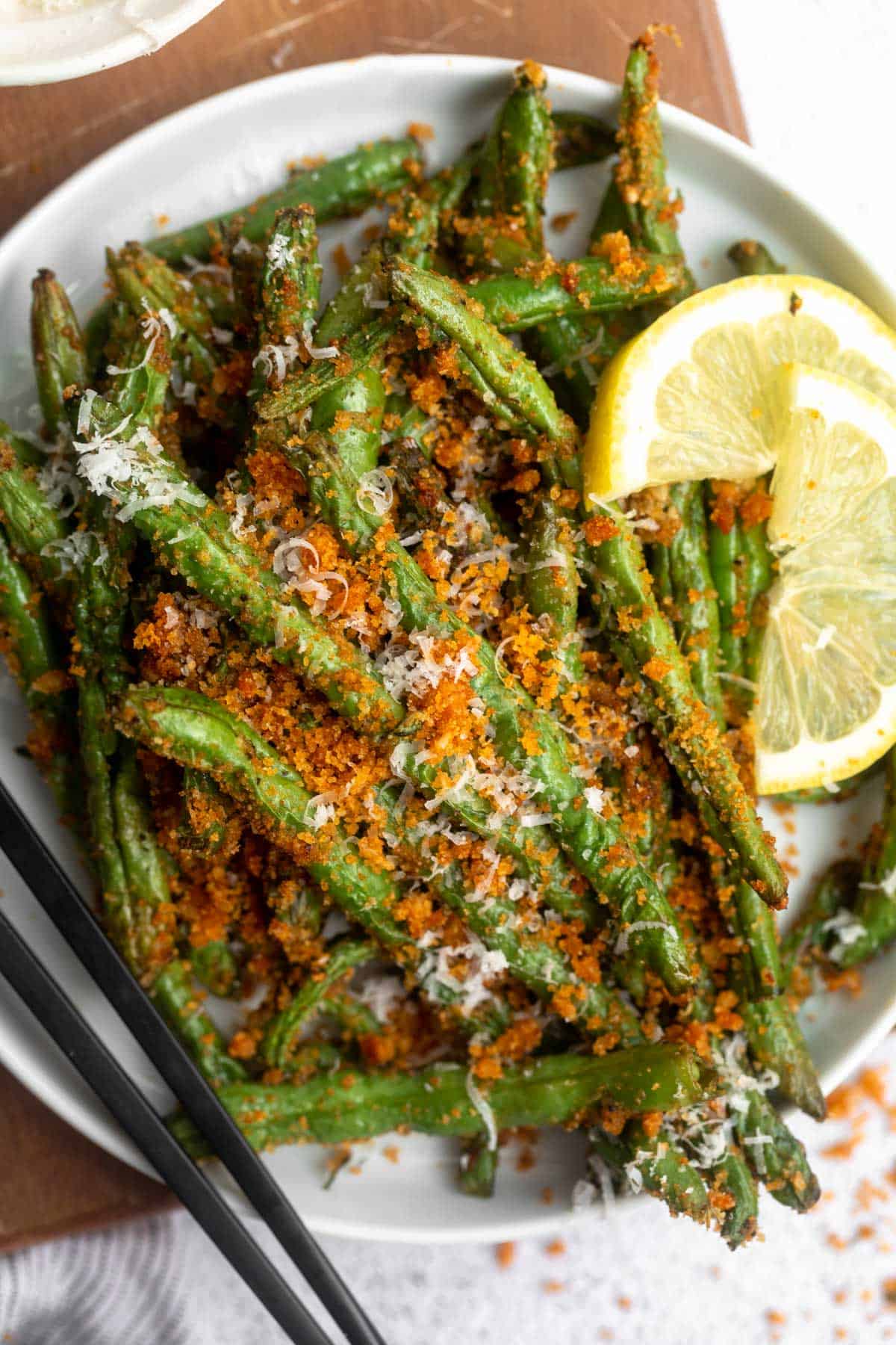 overhead shot of air fryer green beans with lemon on the side
