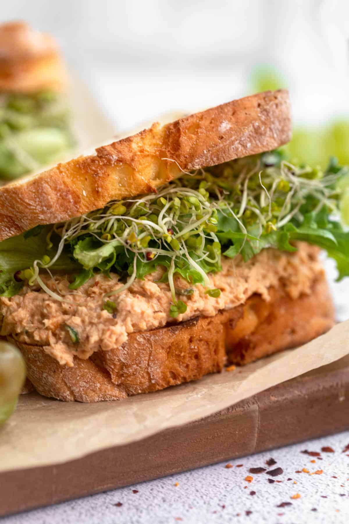 spicy salmon salad sandwich with lettuce and sprouts on top