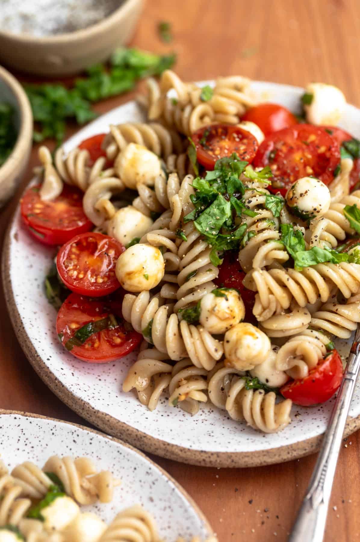 plate with caprese pasta salad with fresh basil on top