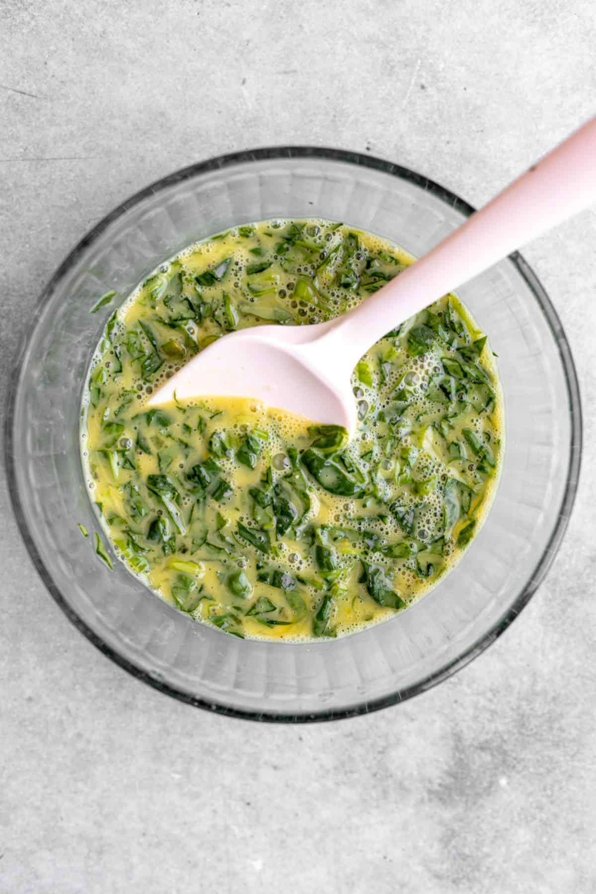 eggs whisked in a bowl with spinach and green onion