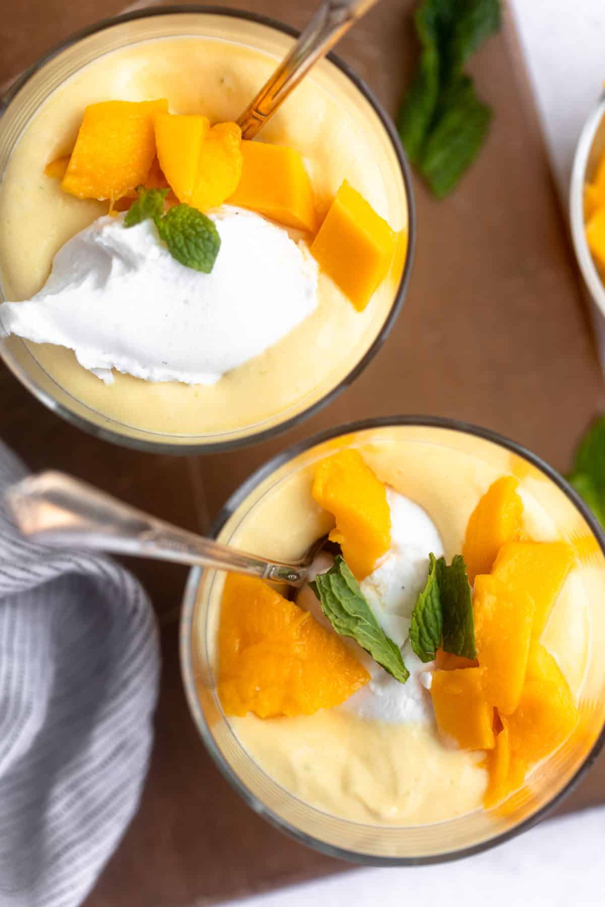 overhead shot of two jars of the mango mousse with whipped cream on top